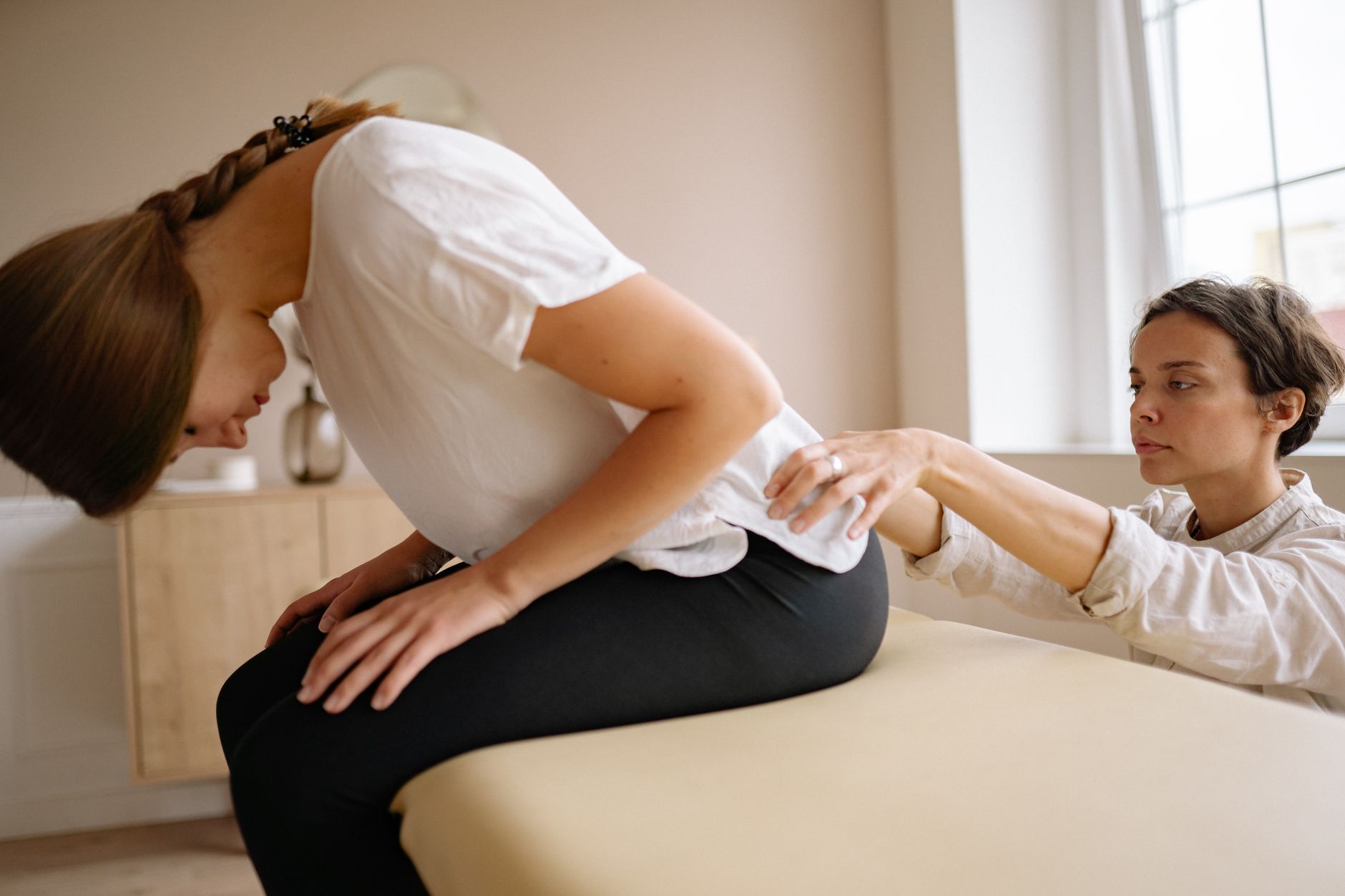 A therapist assists a patient with back rehabilitation exercises in a well-lit clinic.