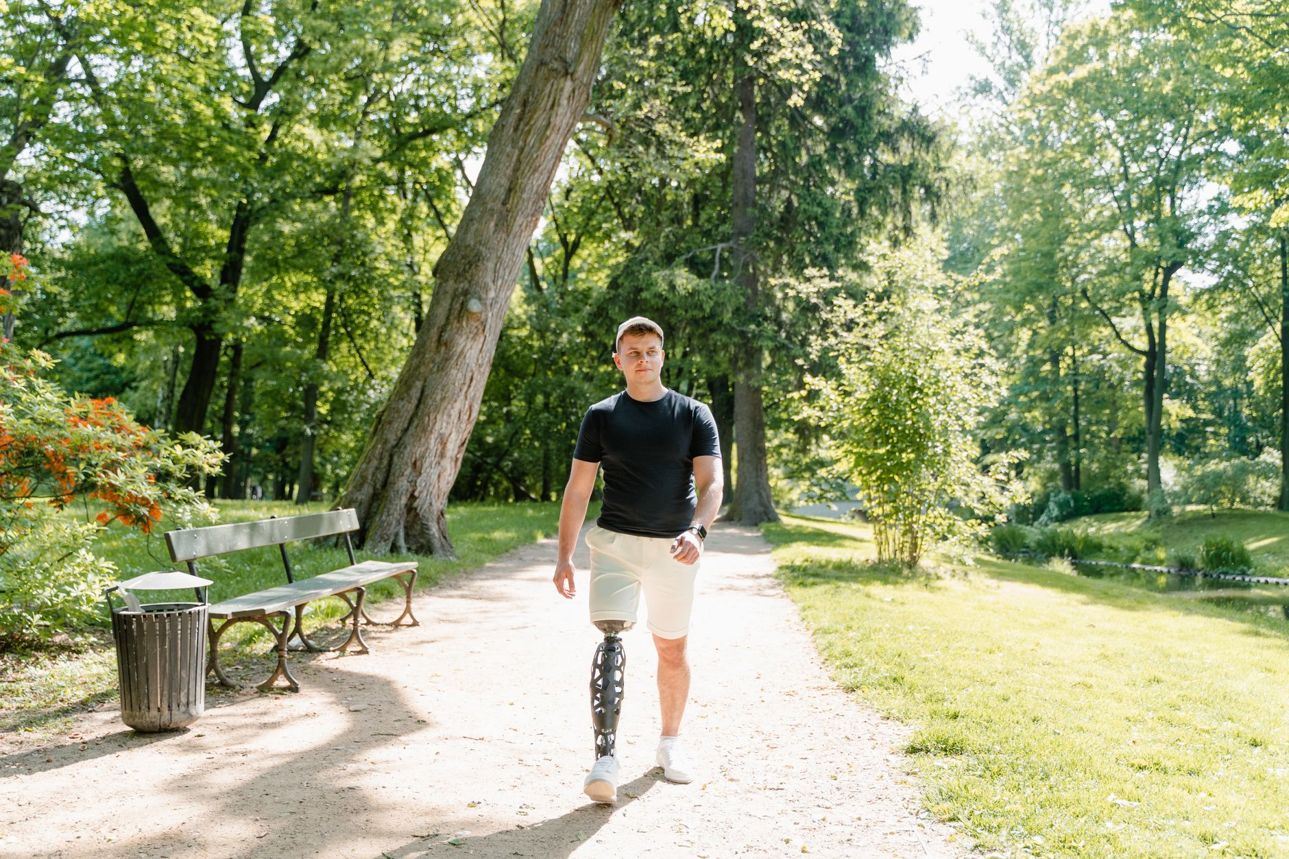 A man with a prosthetic leg walking confidently in a lush green park.