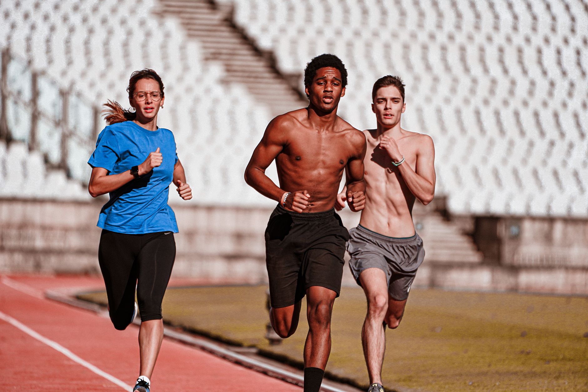 Three athletes running on an outdoor track, showcasing fitness and recovery.