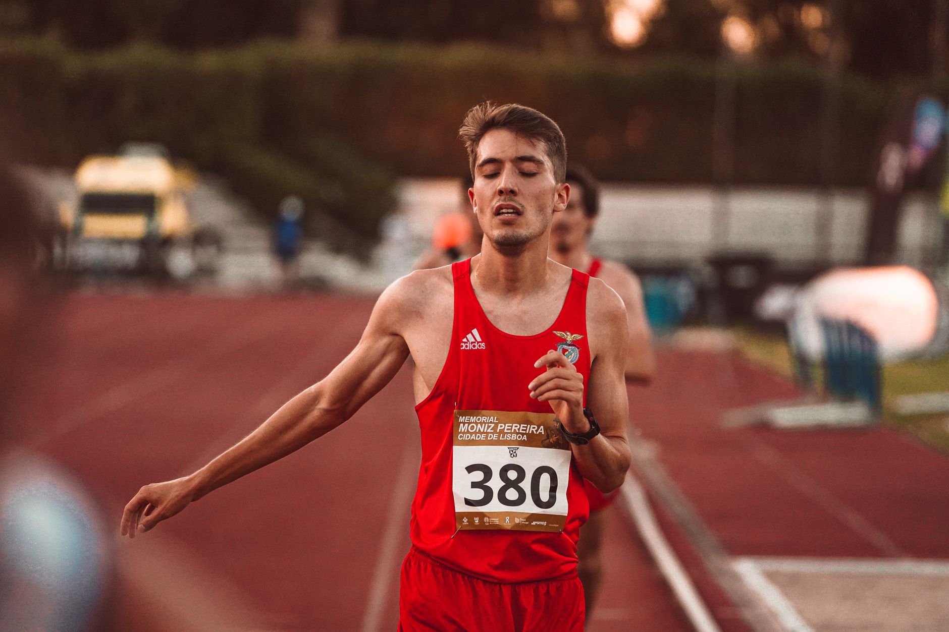 Runner in red jersey with number 380 finishing a race on the track.