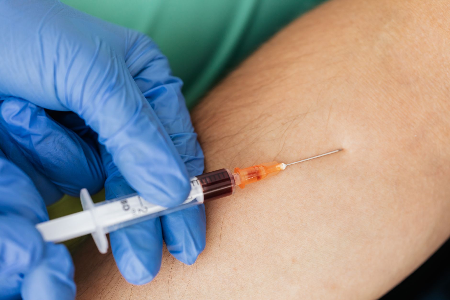 Close-up of a healthcare professional drawing blood with a syringe from a patient's arm.