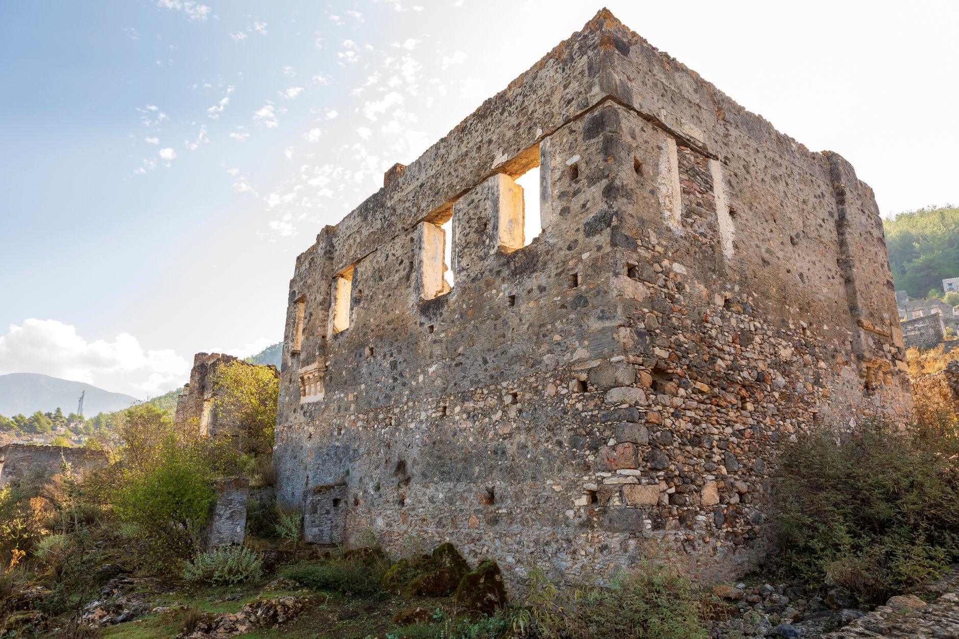 Muğla köyü manzarasında pencereleri olan eski bir taş binanın kalıntıları.