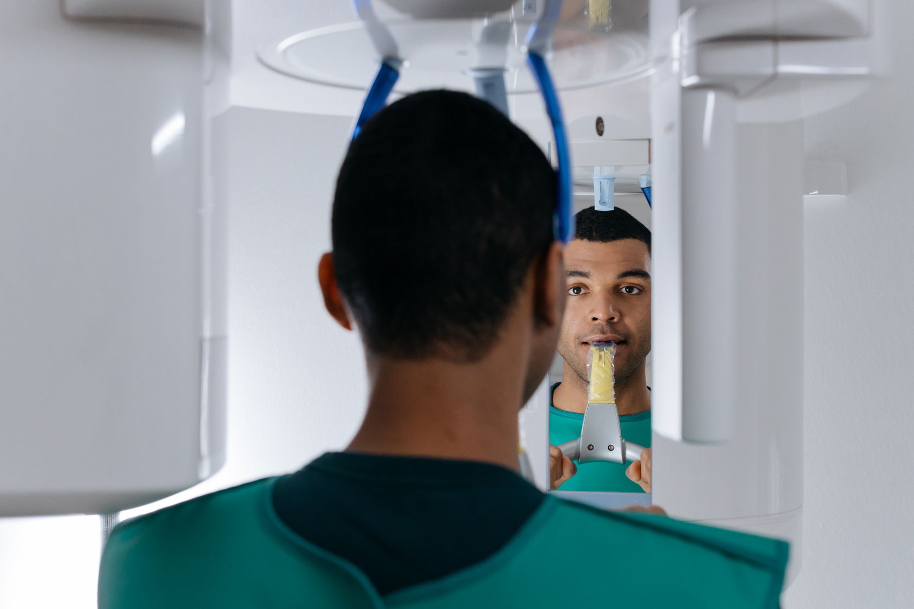 A patient in a dental clinic positioned for a 3D CBCT scan, showcasing the scanning apparatus.