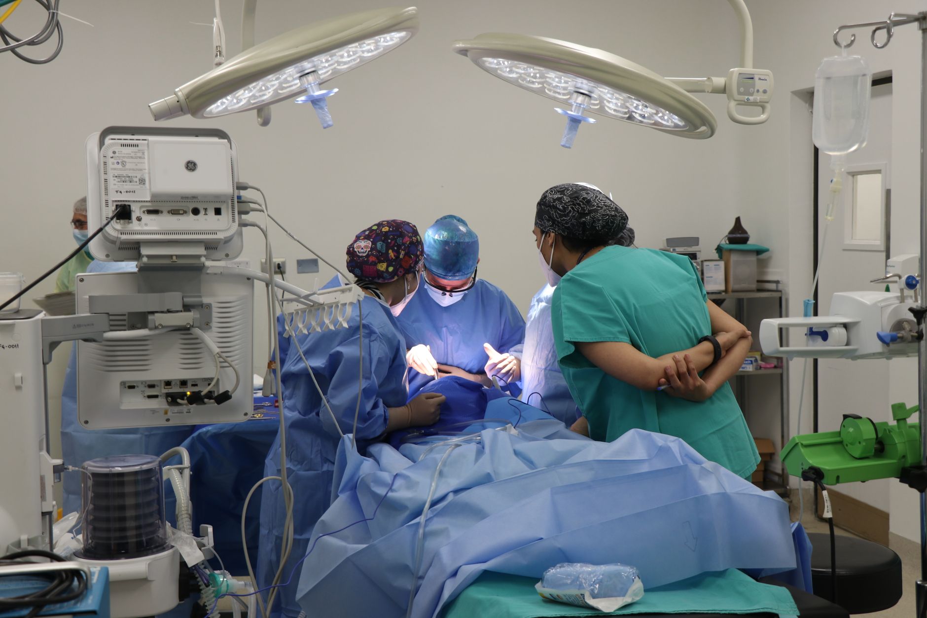 Surgeon and team conducting thyroid surgery with monitoring equipment in an operating room.