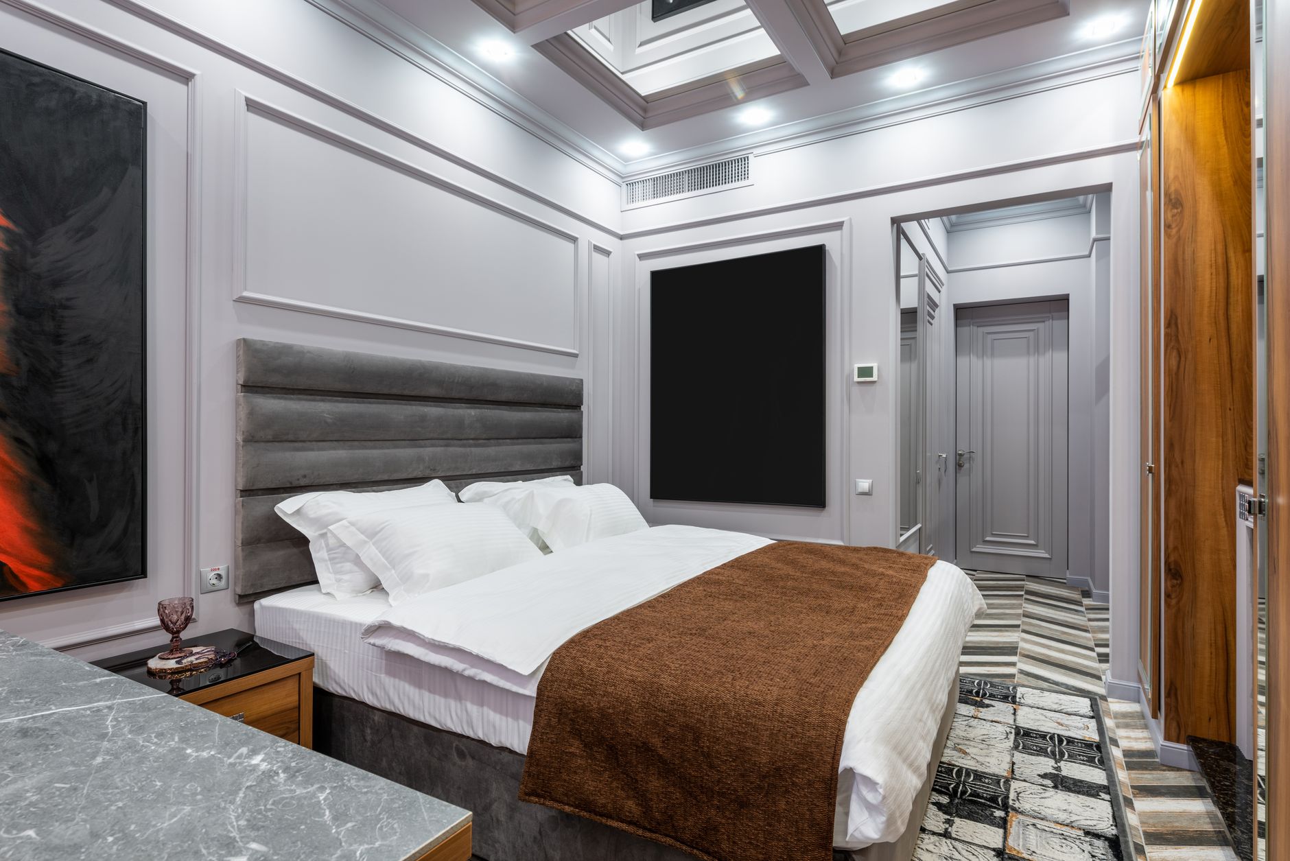 Stylish modern bedroom featuring grey accents, plush bedding, and inviting decor for patient comfort.