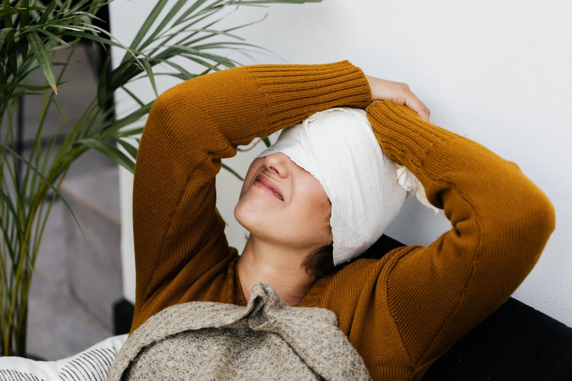 A patient with a bandaged head relaxes on a couch in a serene Izmir clinic.