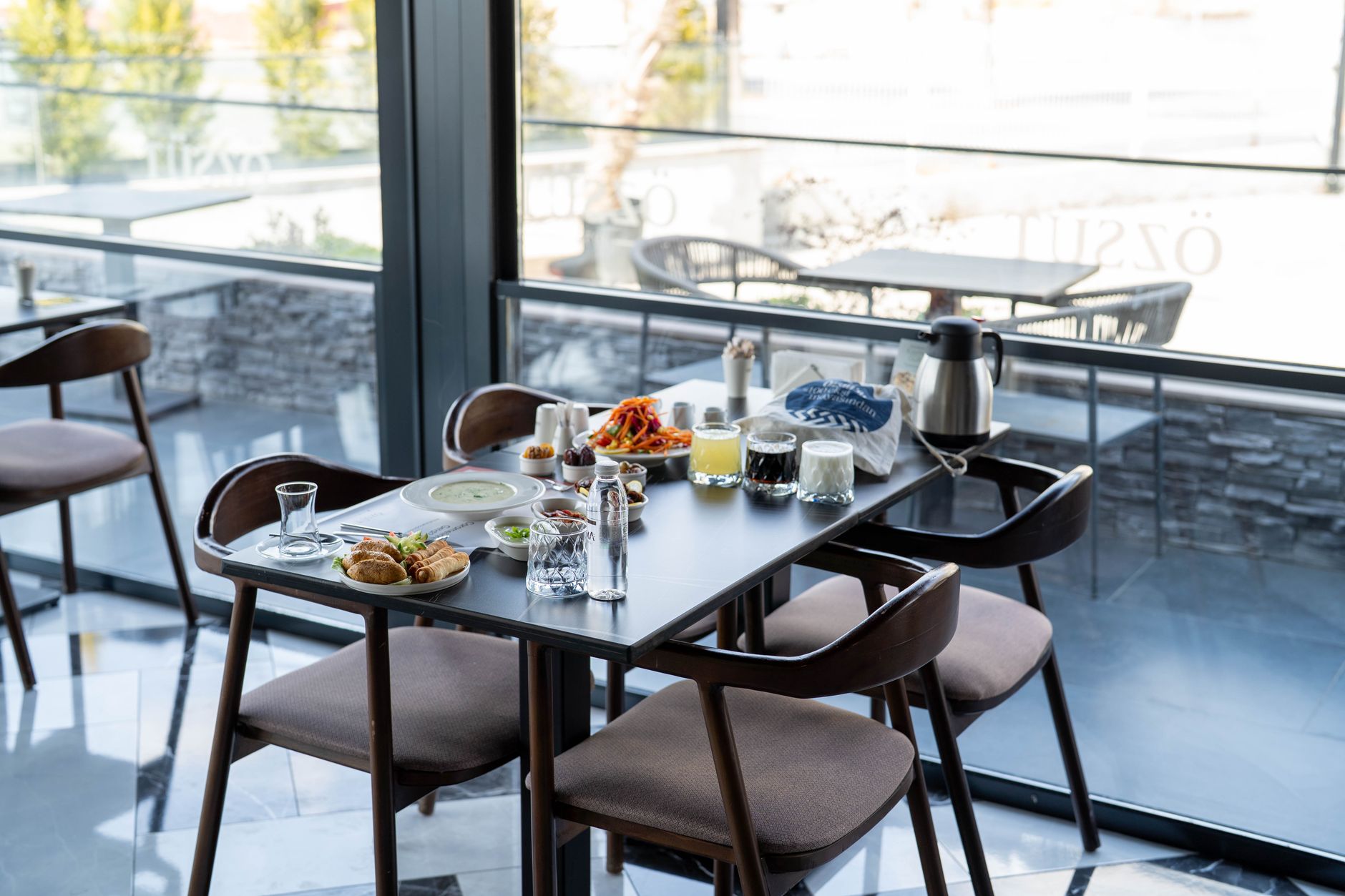 A table set with a variety of food and drinks in a hospital cafe, featuring modern decor.