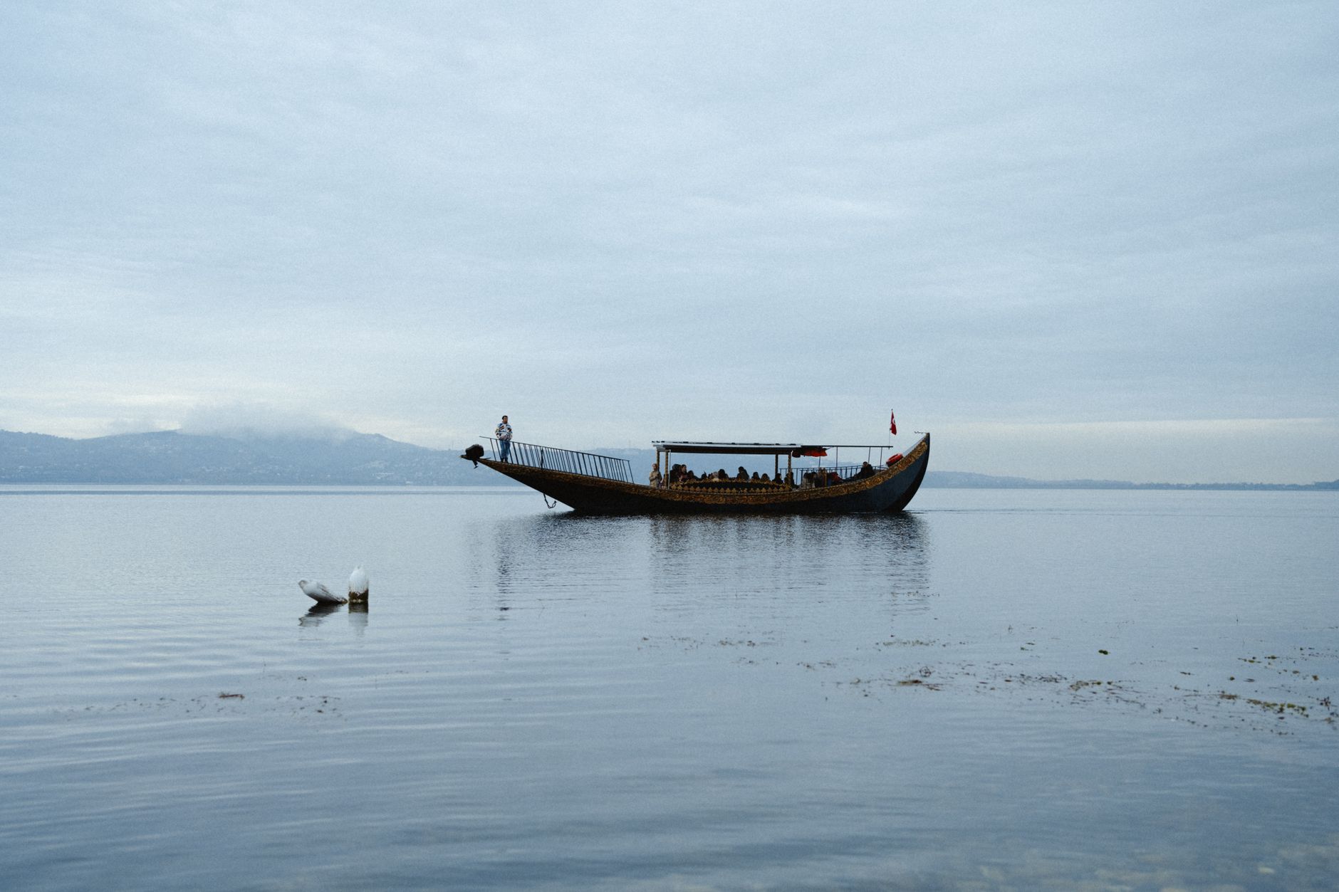 A beautifully decorated boat on the calm waters of Sapanca Lake under a cloudy sky.