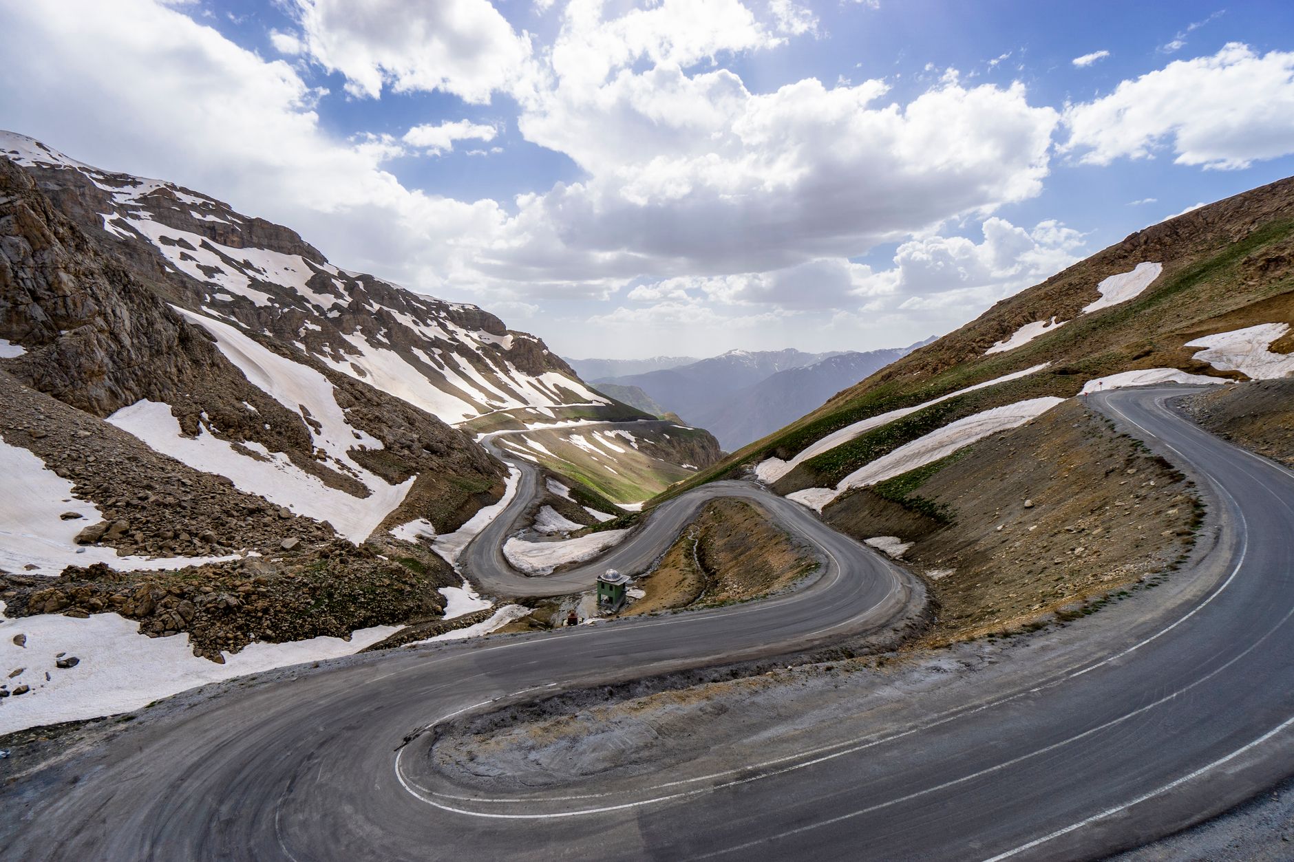 Doğu Türkiye'de karla kaplı dağlarla çevrili kıvrımlı çakıl yol.