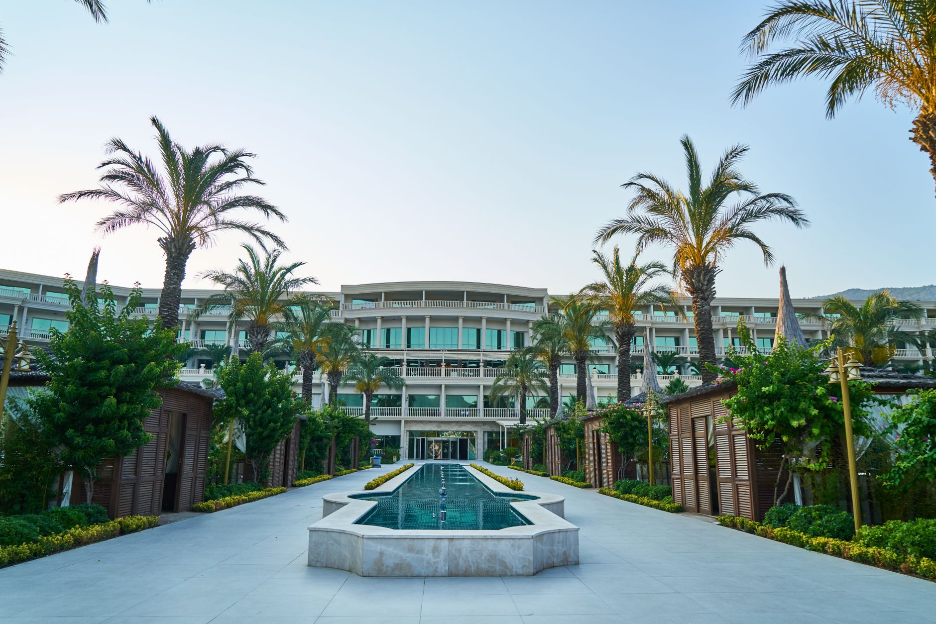 Elegant entrance of Bursa thermal spa resort lined with palm trees and greenery.