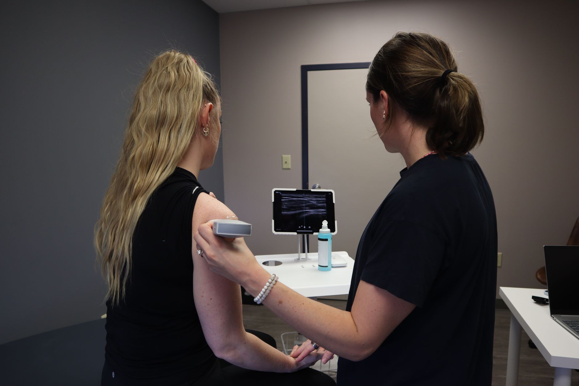 A clinician performing a Doppler ultrasound vascular assessment on a patient's arm.