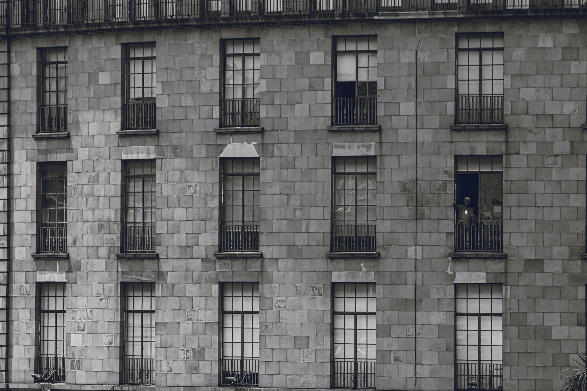 Facade of a historic building in Mexico City with windows and a person on the balcony.