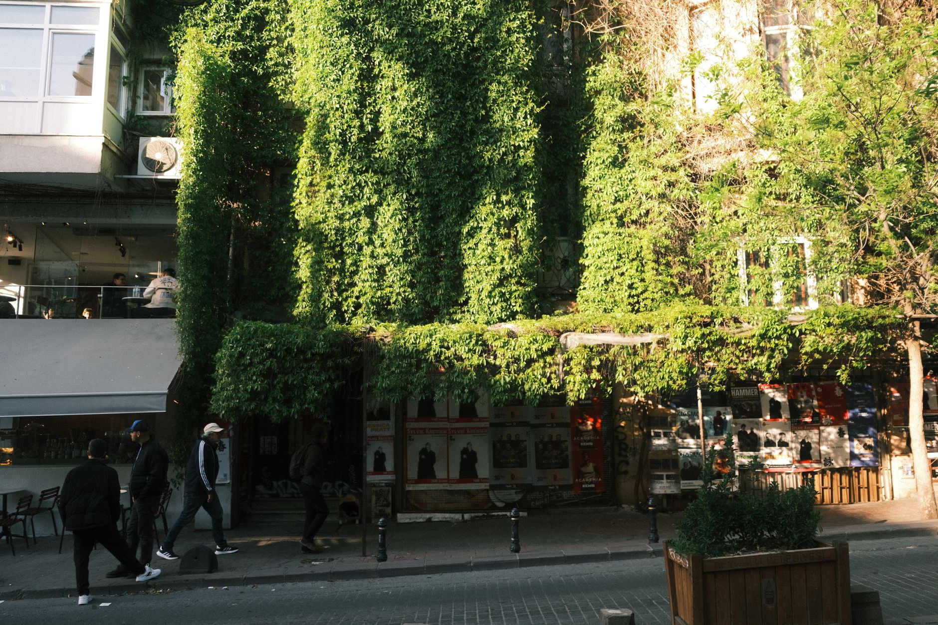 A lush green facade covering a building in Nişantaşı, Istanbul, with people walking by.