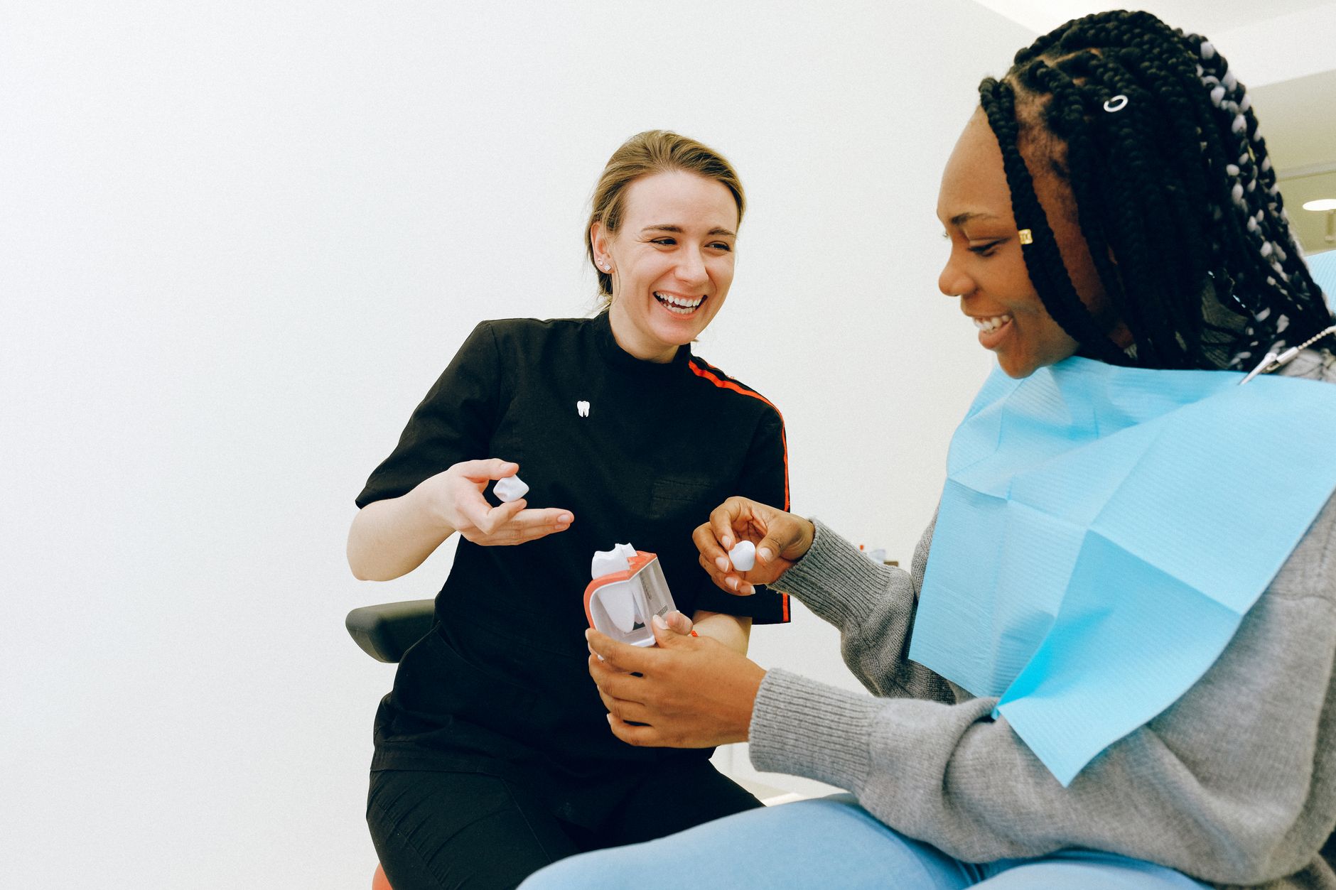 A prosthodontist and patient smiling while discussing a dental treatment plan in a clinical setting.