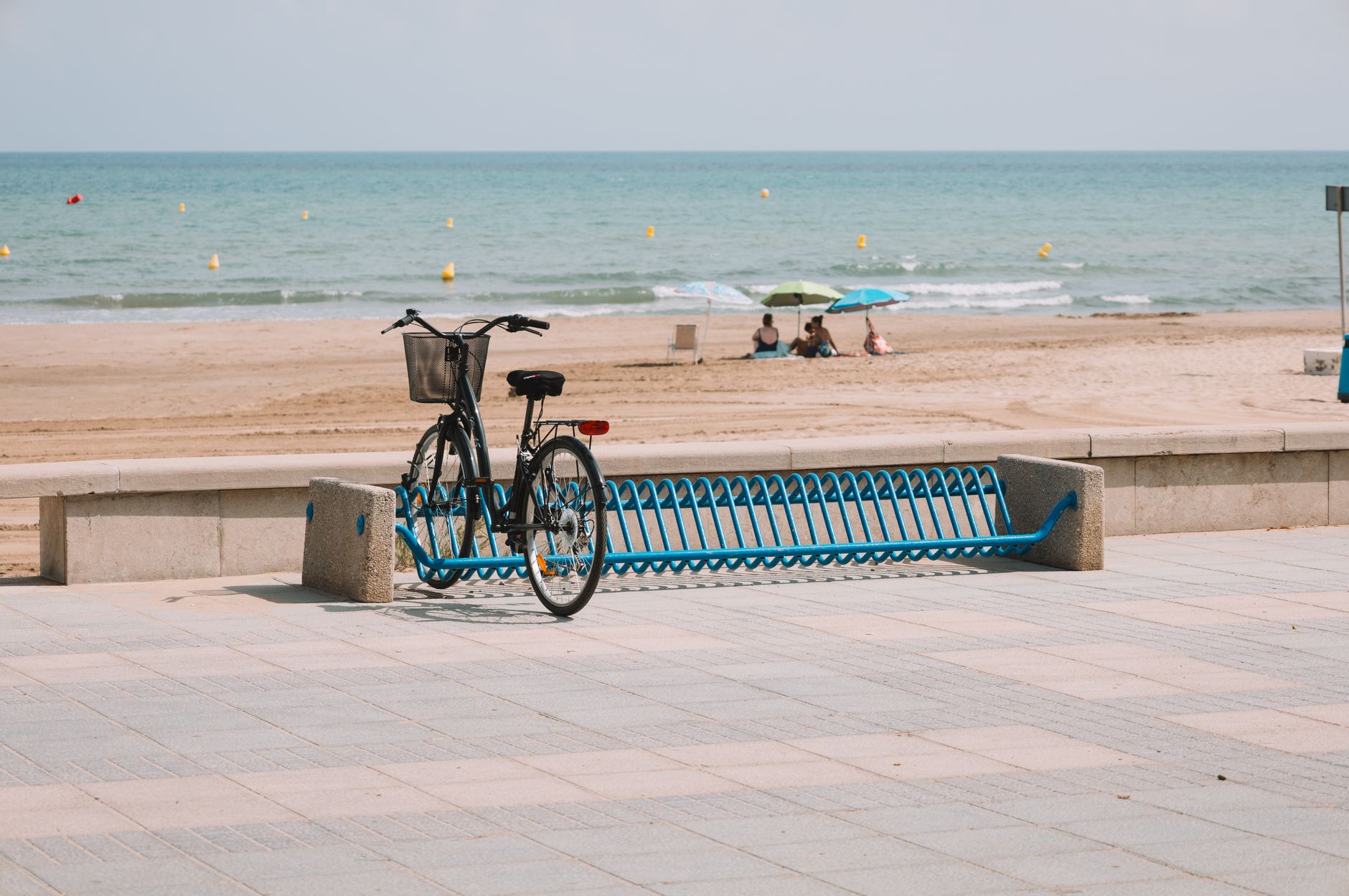 A bicycle parked near a calm beach in Spain, ideal for recovery after cosmetic surgery.