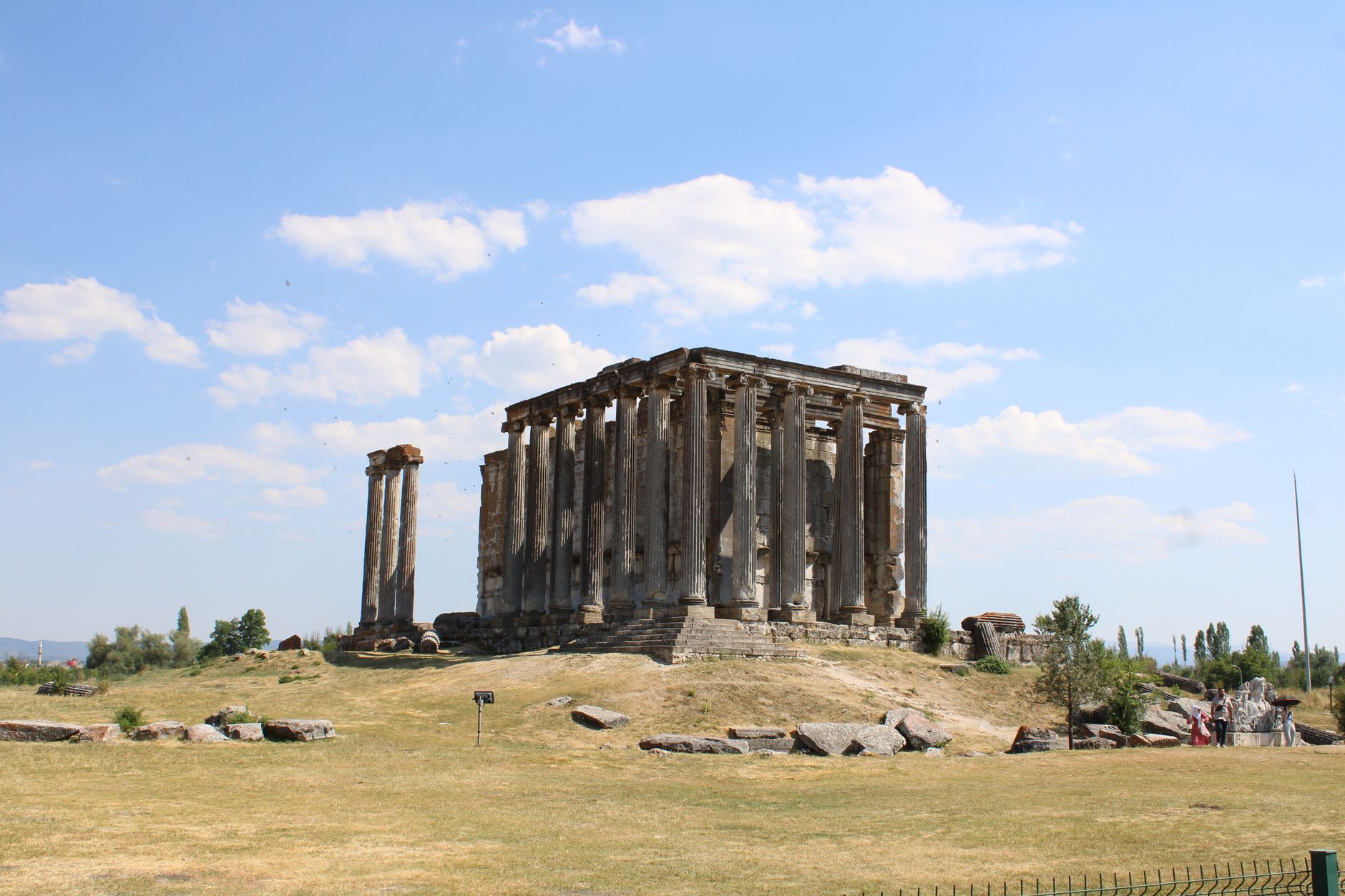 A view of the ancient Roman temple ruins with several standing columns under a clear blue sky.