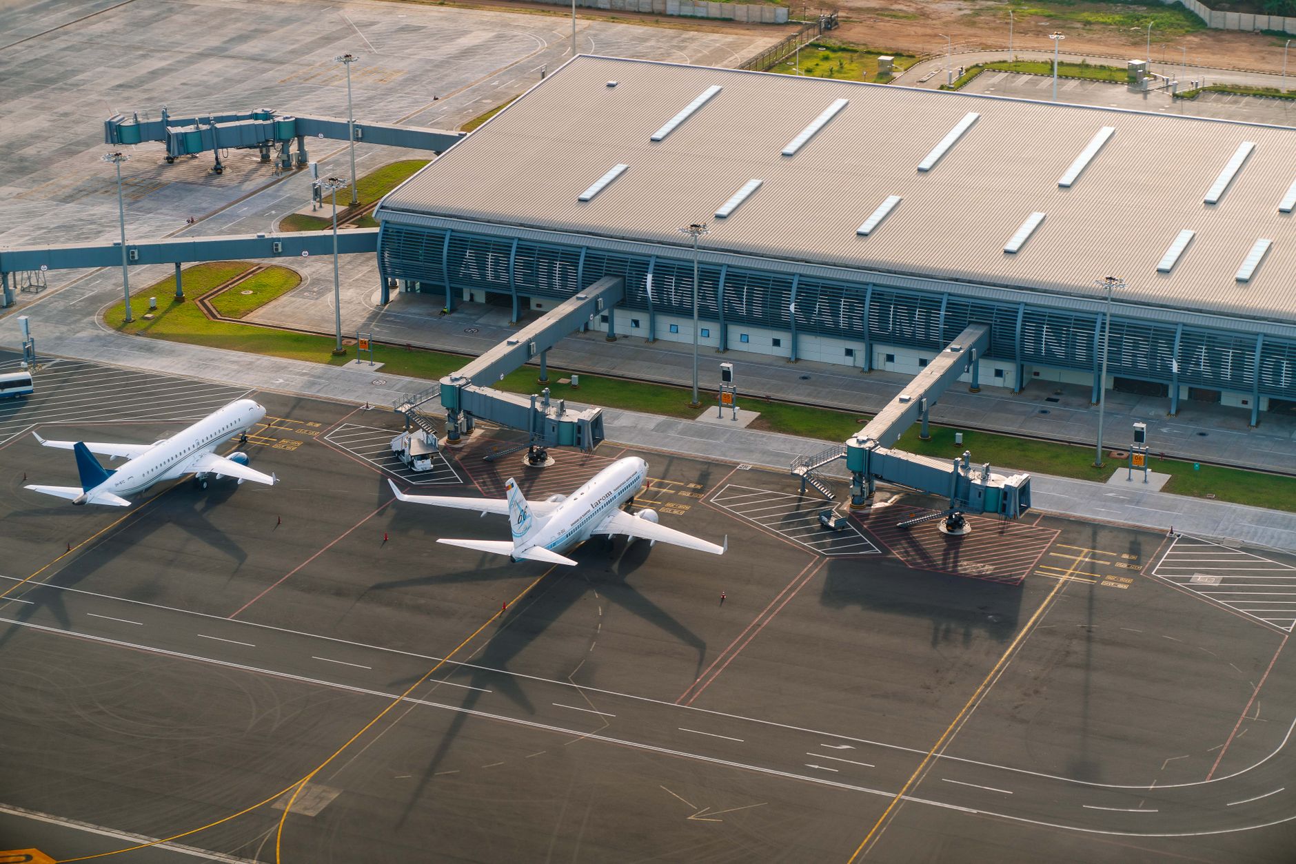 Aerial view of an airport in Indonesia with three parked planes at terminal gates.