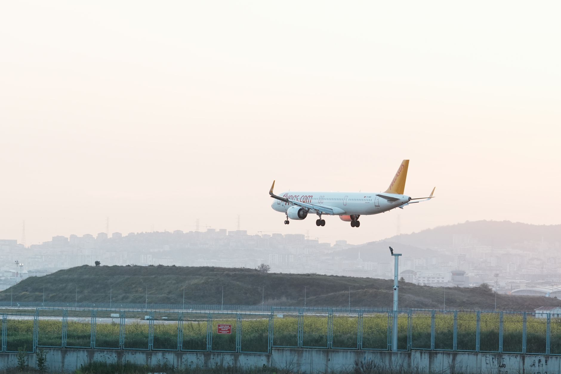 A Turkish Airlines plane approaches the runway at Istanbul Airport during sunset.
