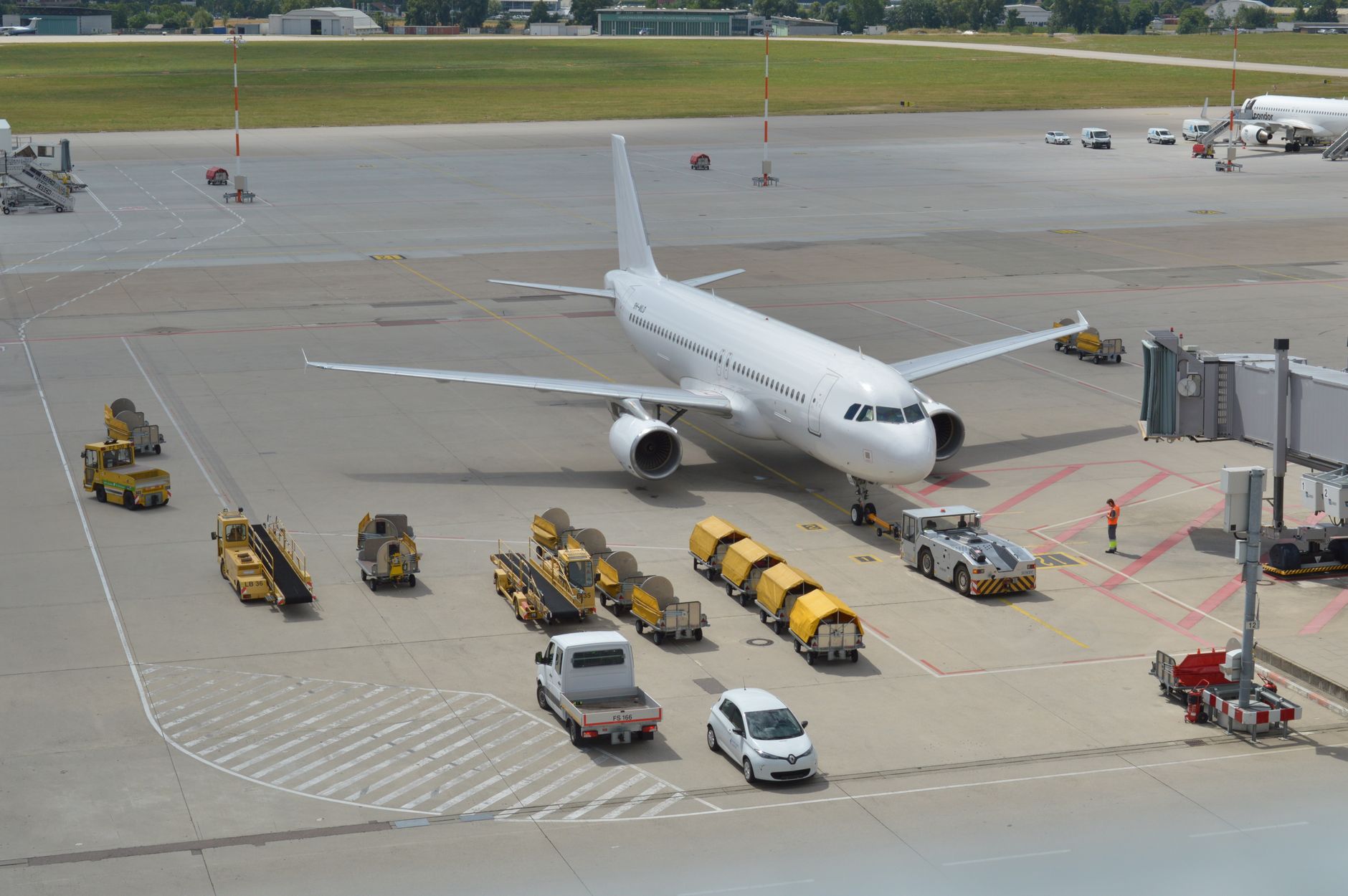 An airport scene showing a white airplane with ground personnel managing medical equipment.