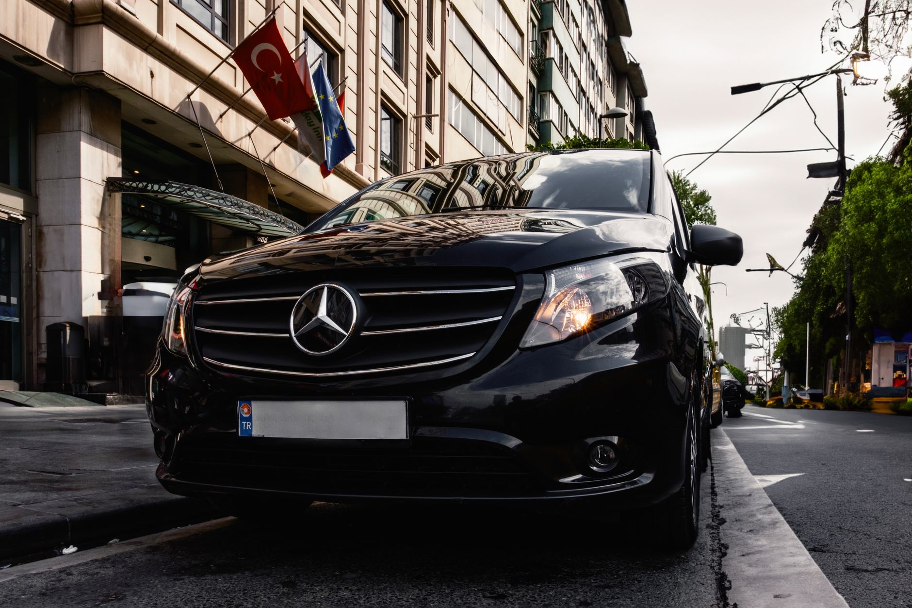 A black Mercedes van parked outside a building, waiting for patient transfer at a Turkish location.