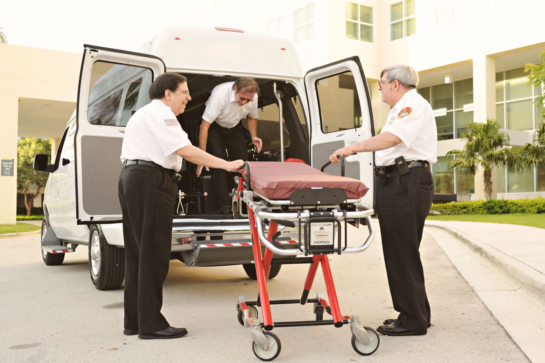 Medical team loading a stretcher from an ambulance at the airport.