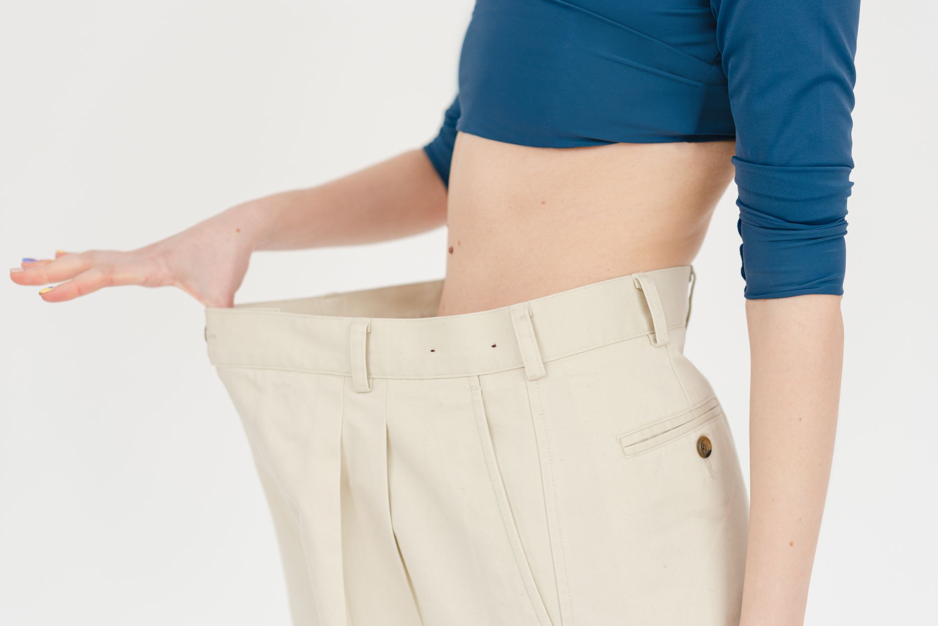 A person shows off loose-fitting pants after successful weight loss following bariatric surgery.