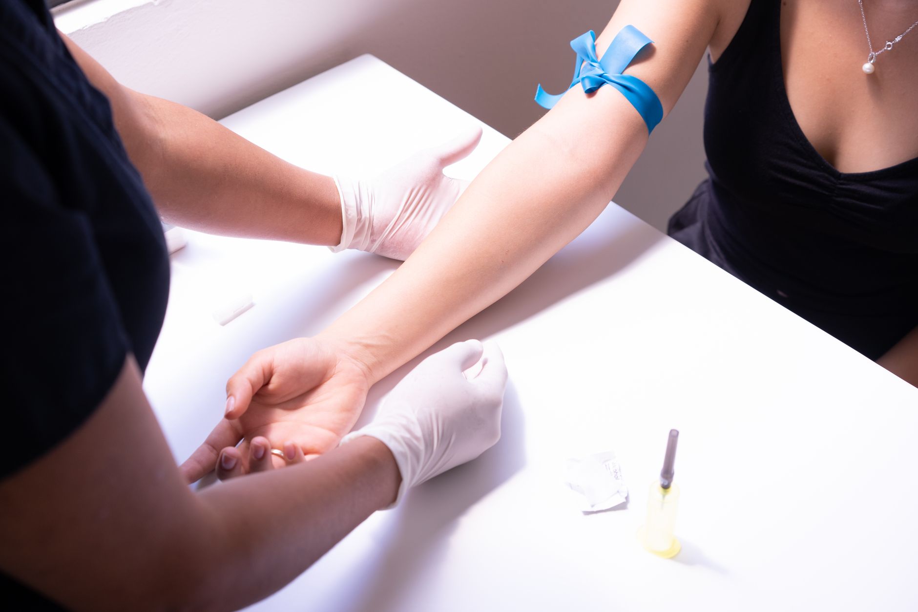 A healthcare professional prepares to draw blood for a test on a patient’s arm.