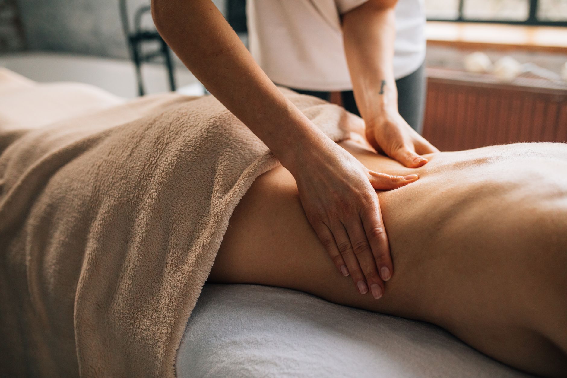 A gentle massage being performed on a patient's back in a calming spa setting.