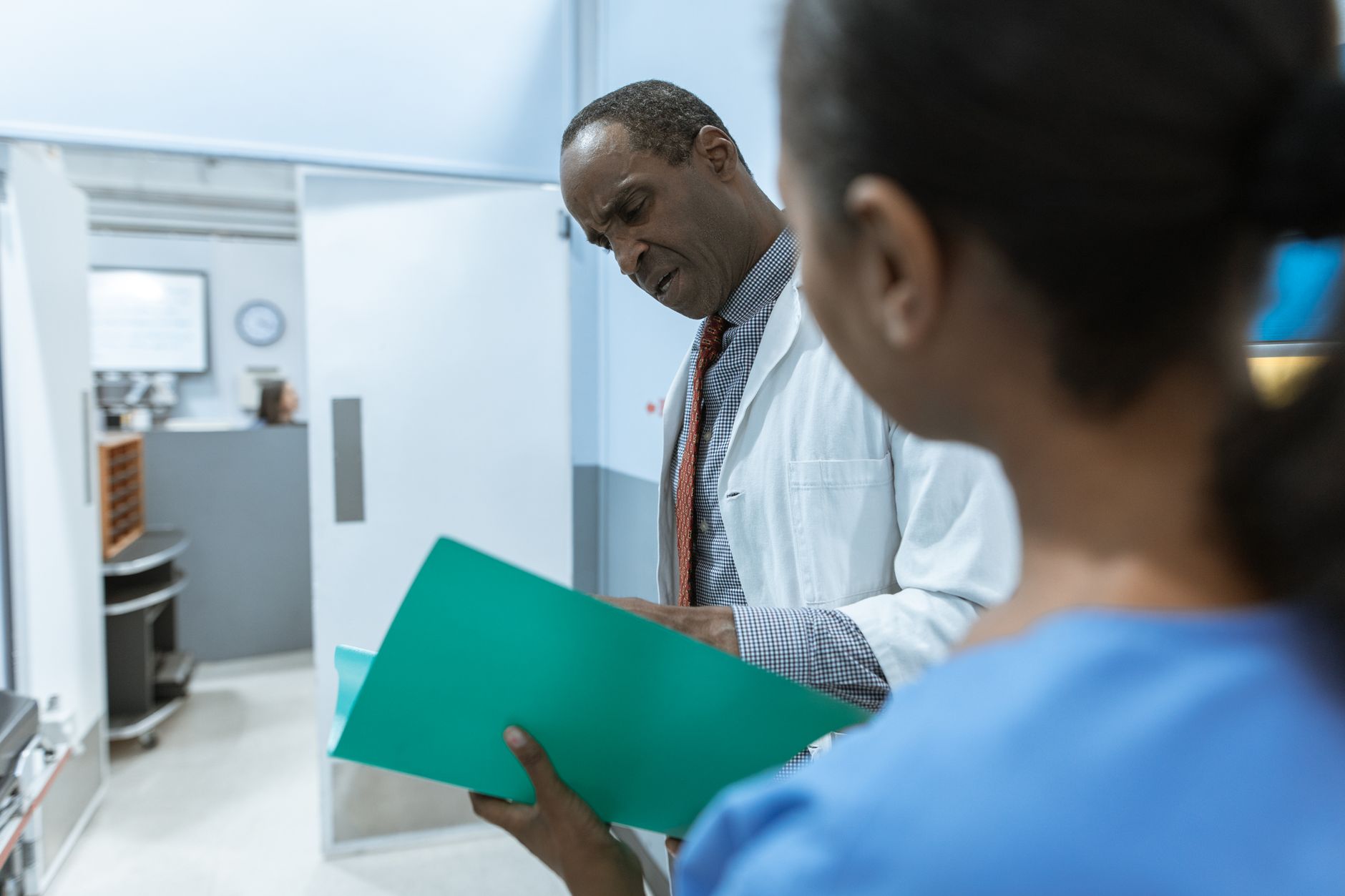Doctor discussing a medical summary with a nurse at a clinic.