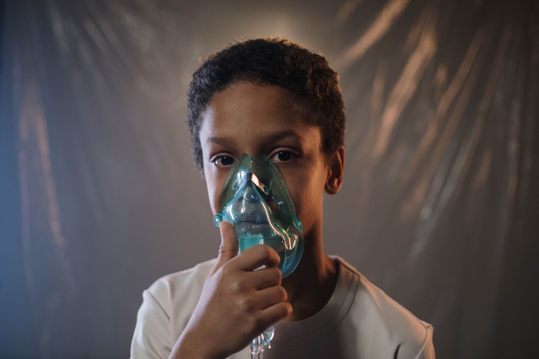 A young boy using an asthma inhaler with a spacer, focused and calm.