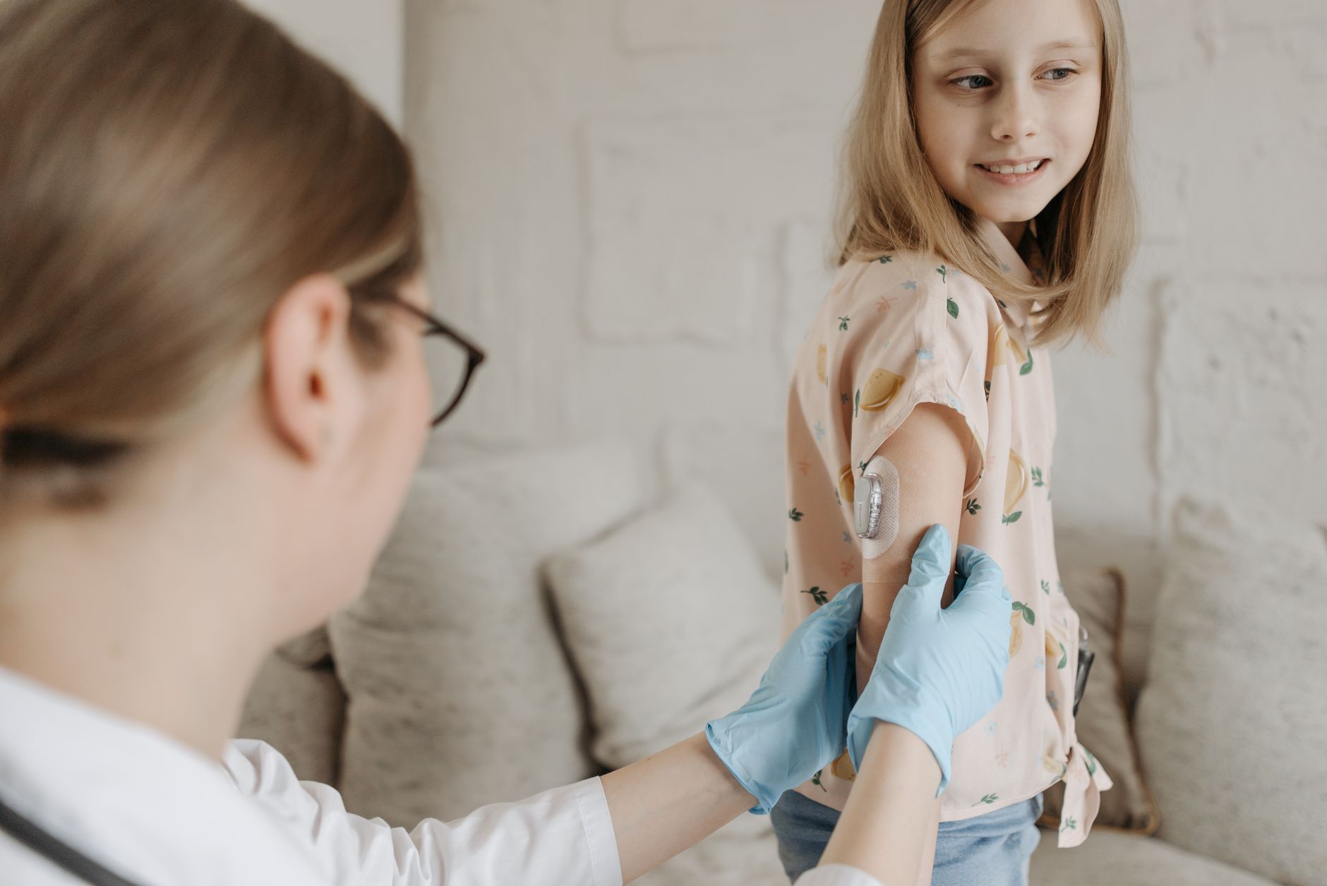 A paediatric nurse is performing a skin prick allergy test on a child's forearm in a modern clinic setting.