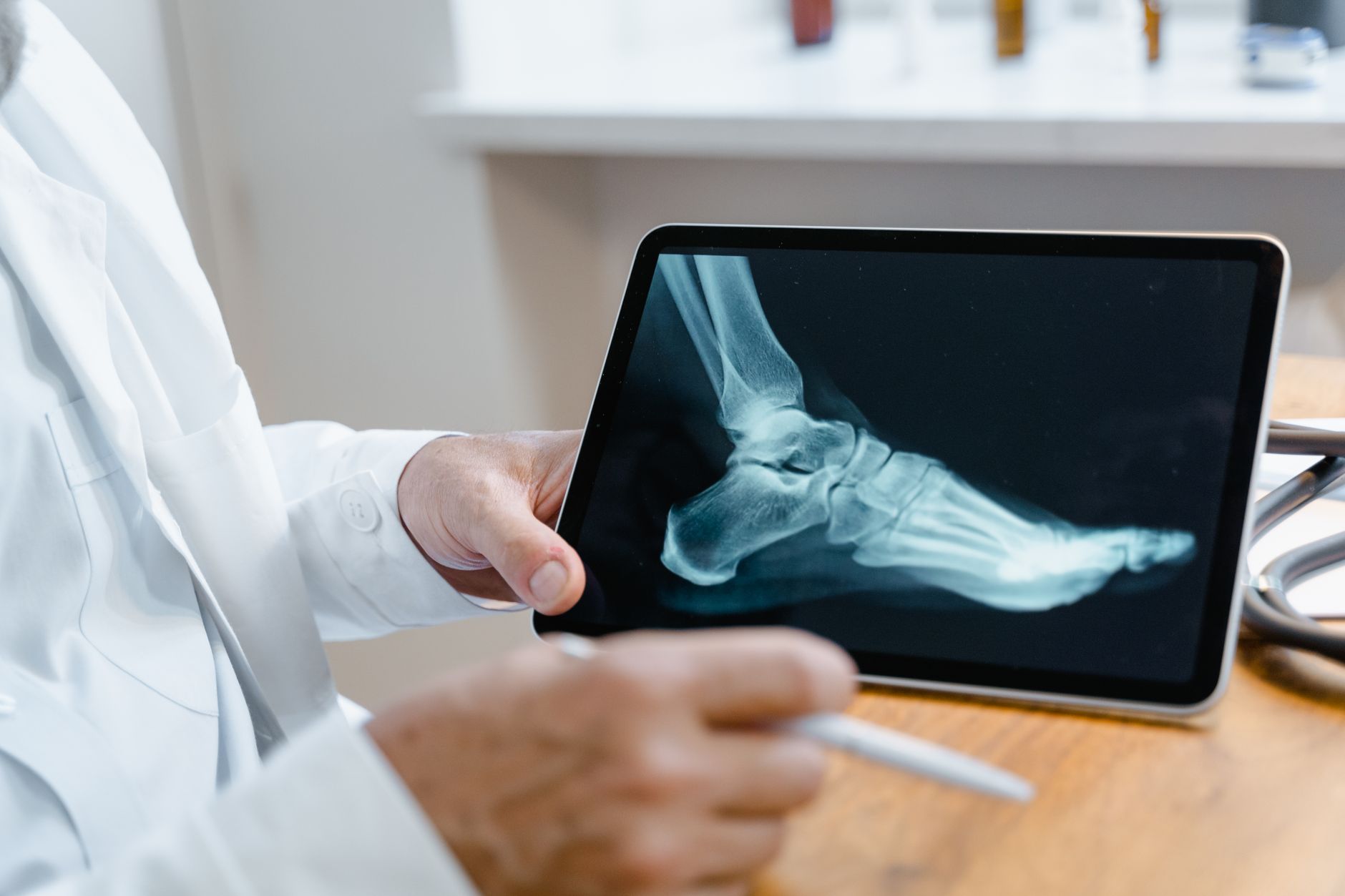 A surgeon reviewing an X-ray scan of a foot on a tablet, showcasing modern medical technology.