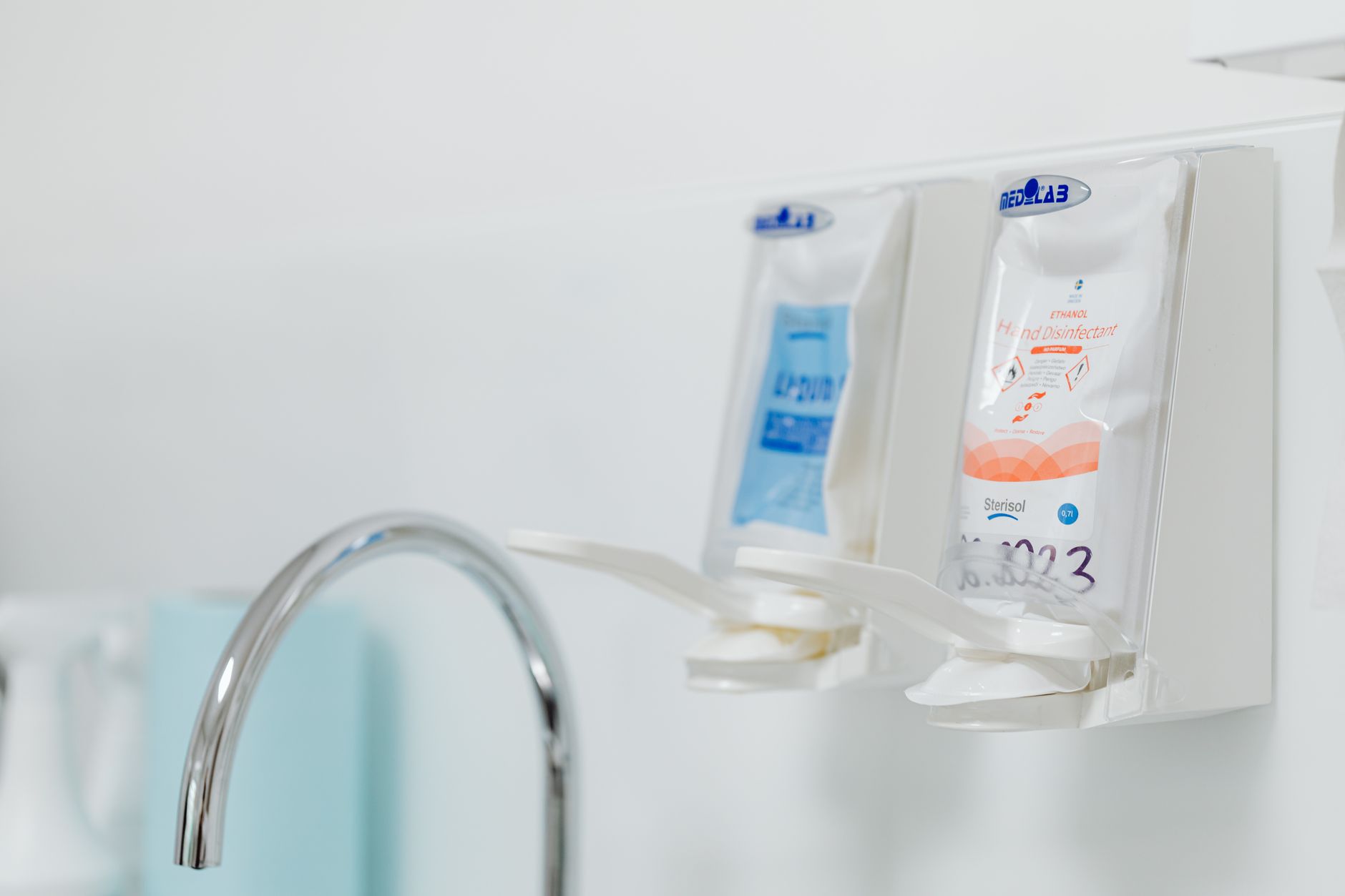 Clinical hand sanitizer stations mounted on a wall with dispensers.