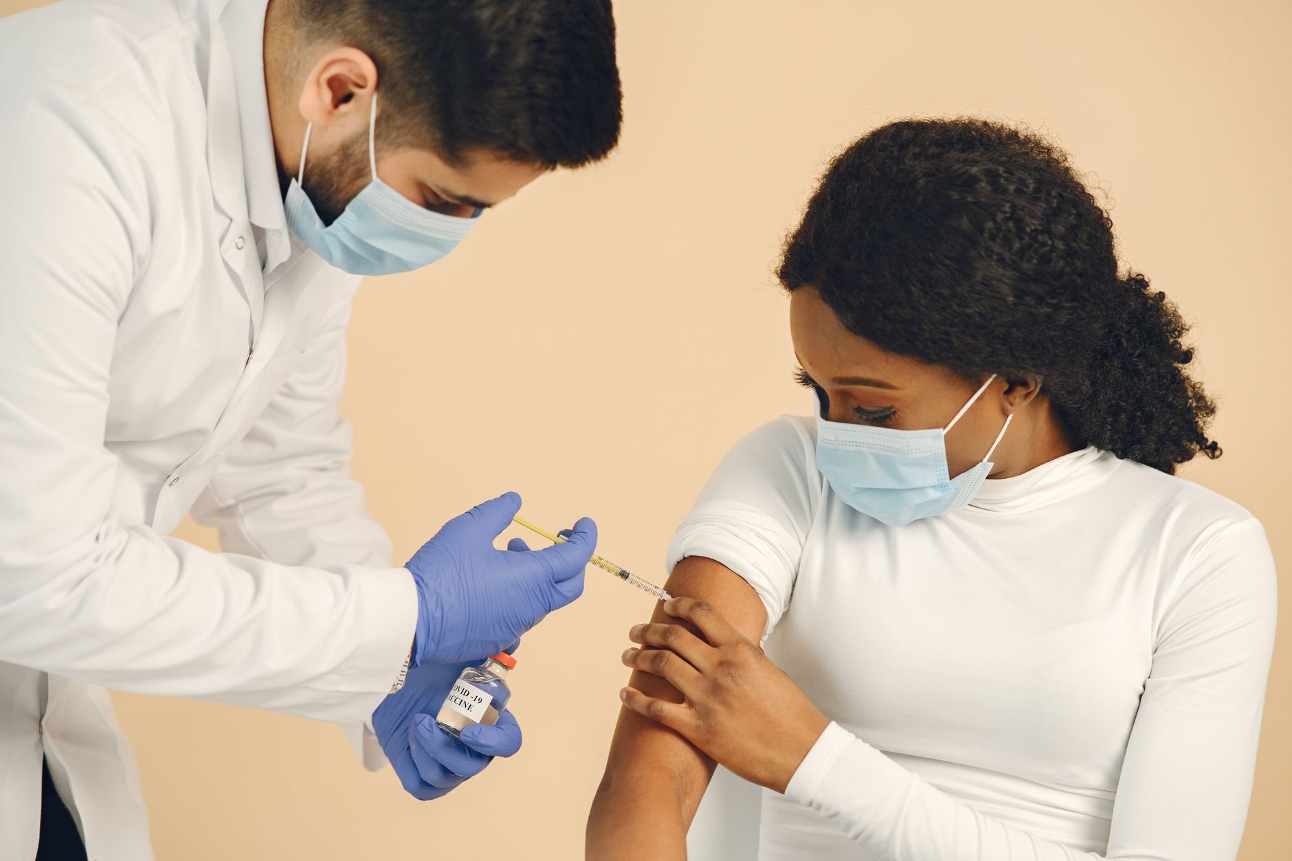 A healthcare worker gives a COVID-19 vaccine to a patient in a clinical setting.