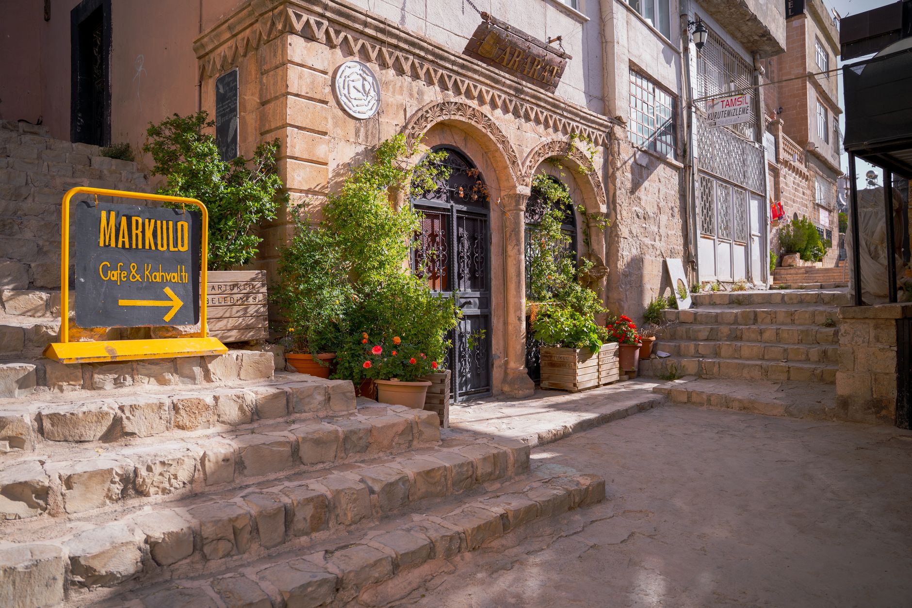Café Markulo in Mardin featuring stone steps and lush plants.