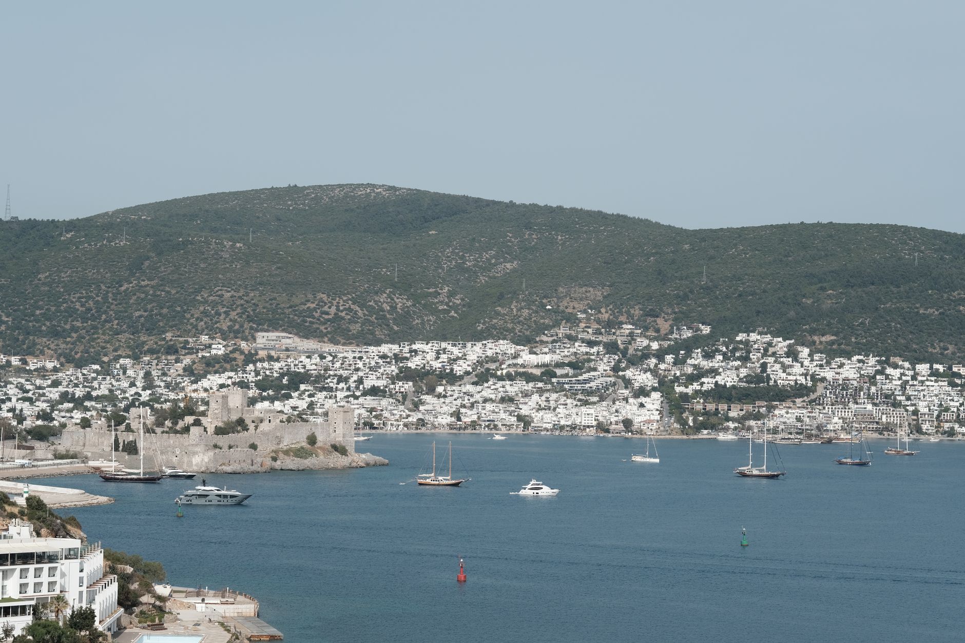 View of the Aegean coastline near Bodrum, featuring white houses and boats on azure waters.