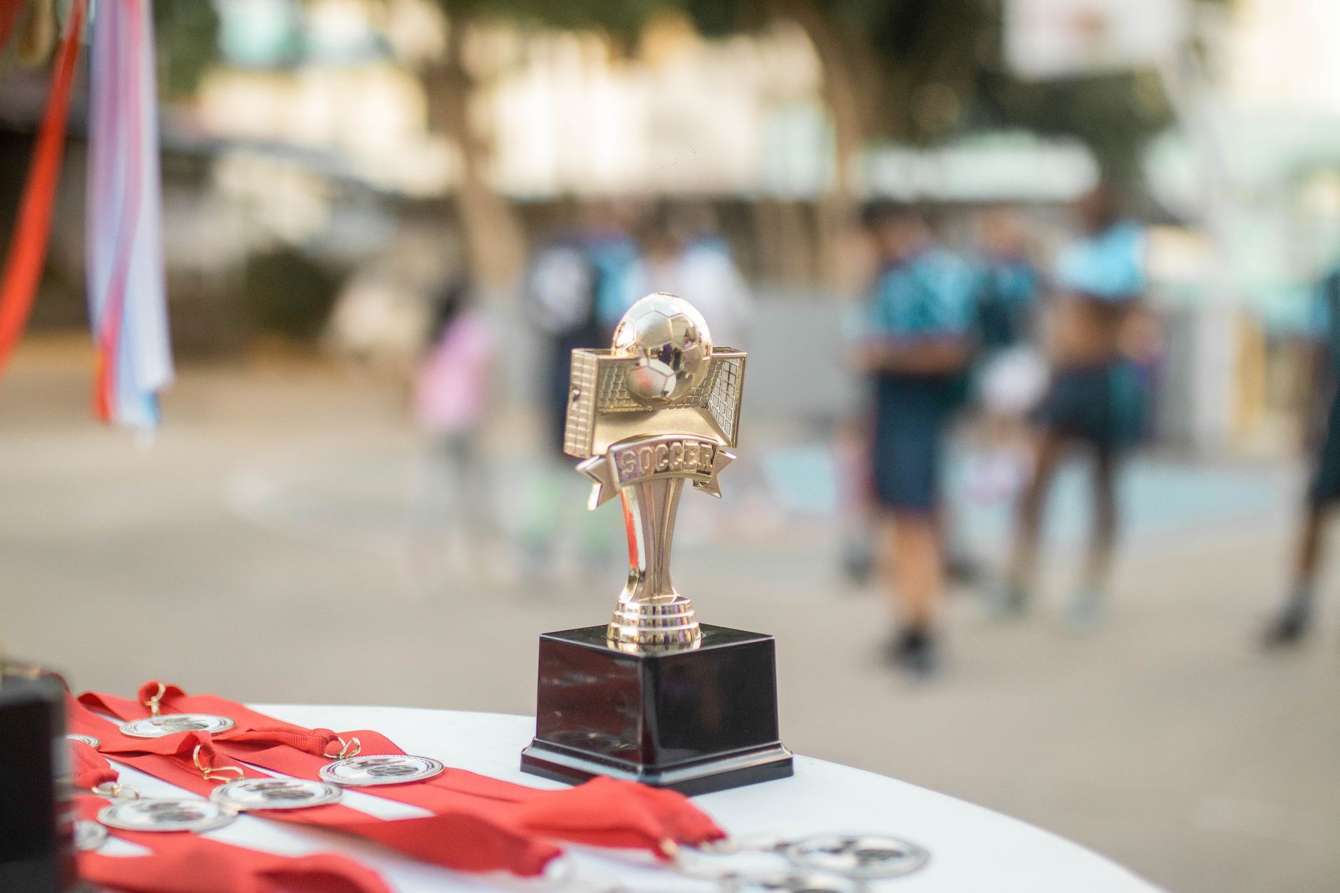 A shiny soccer trophy with medals displayed at an award ceremony.