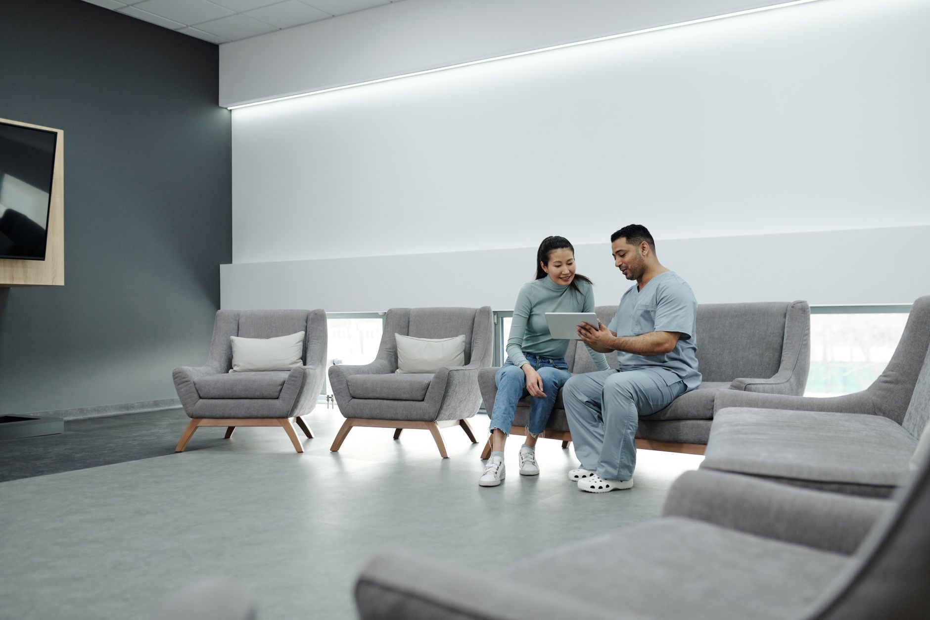 A patient accessing medical records on a tablet while sitting with a healthcare provider in a modern clinic.