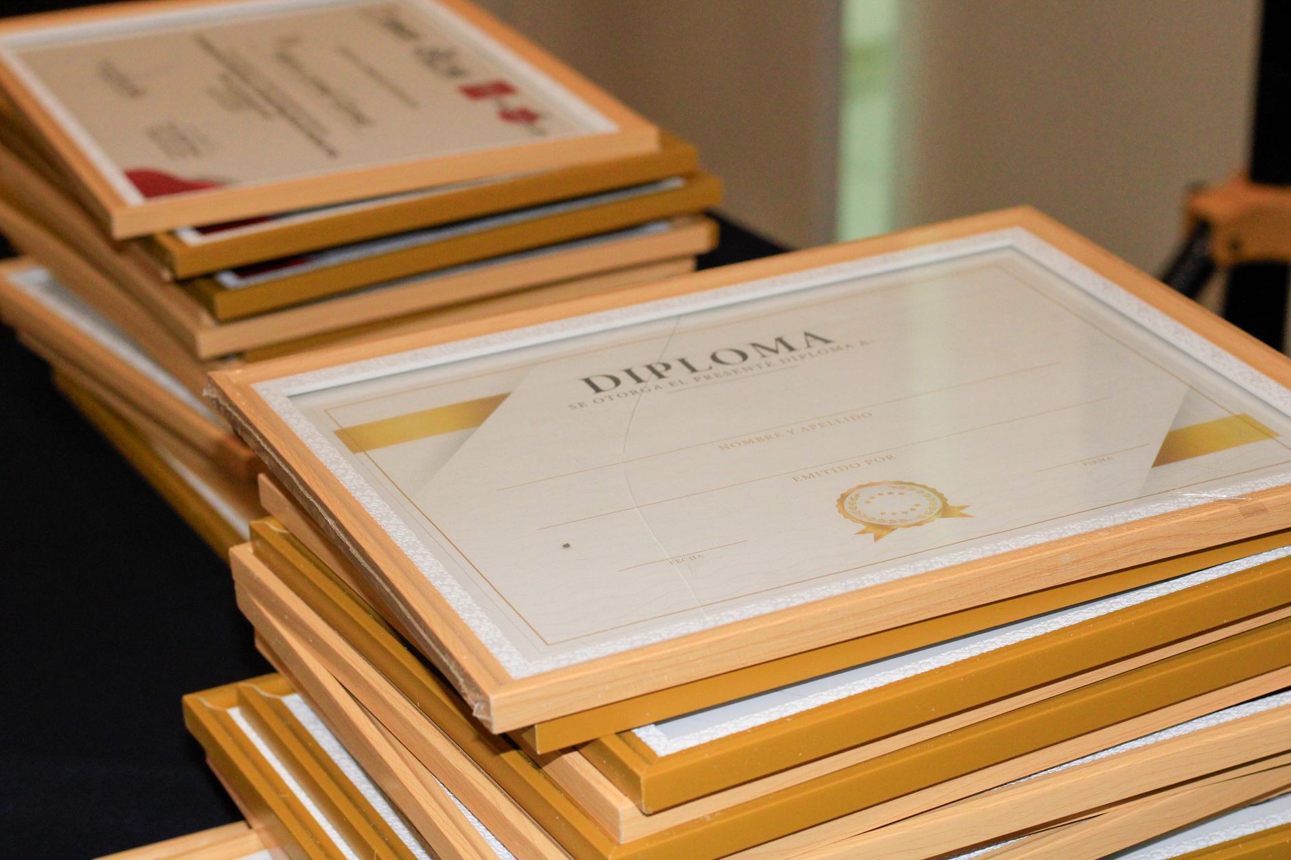 Stack of framed diplomas on a table, ready for an accreditation ceremony.