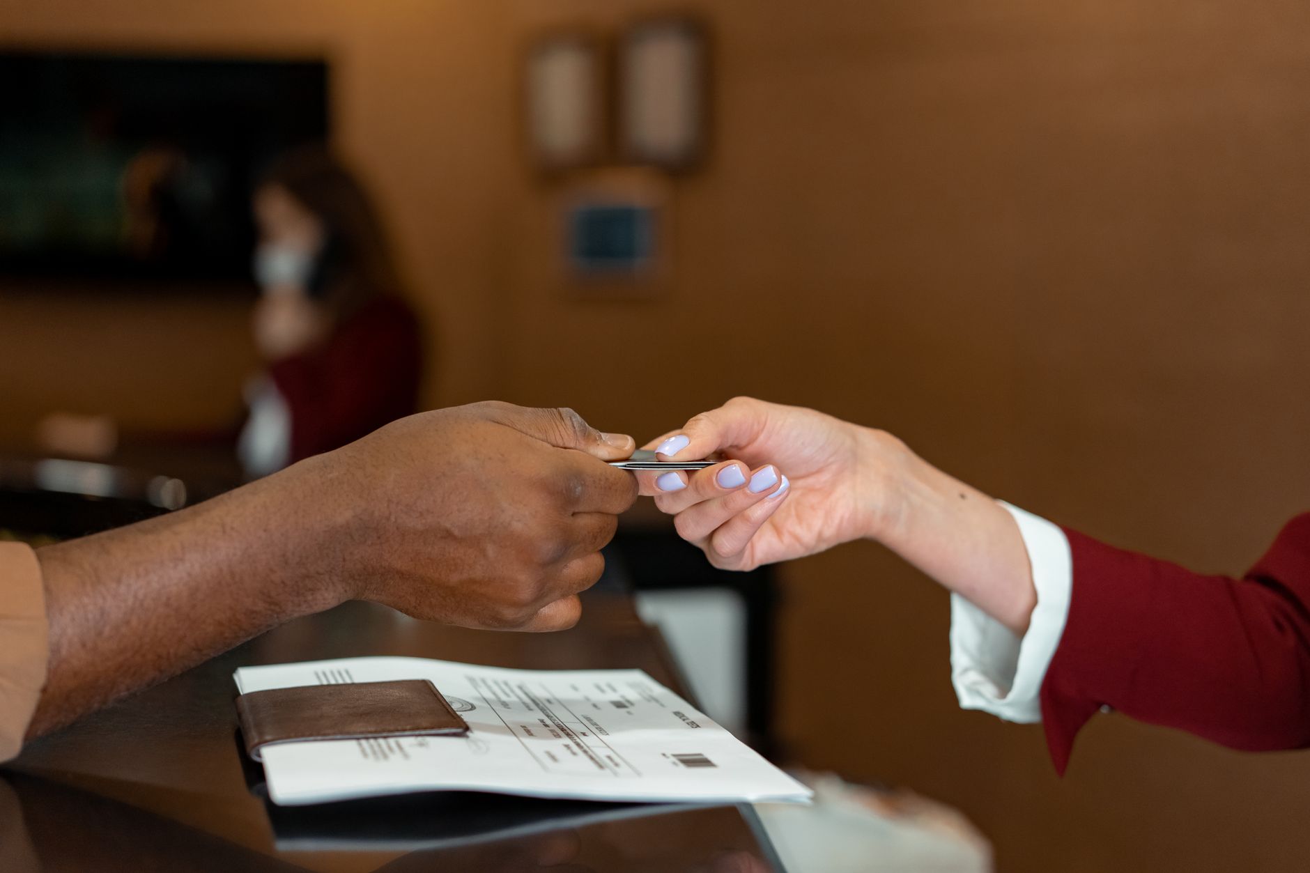 A patient hands a credit card to a hospital receptionist at the desk.