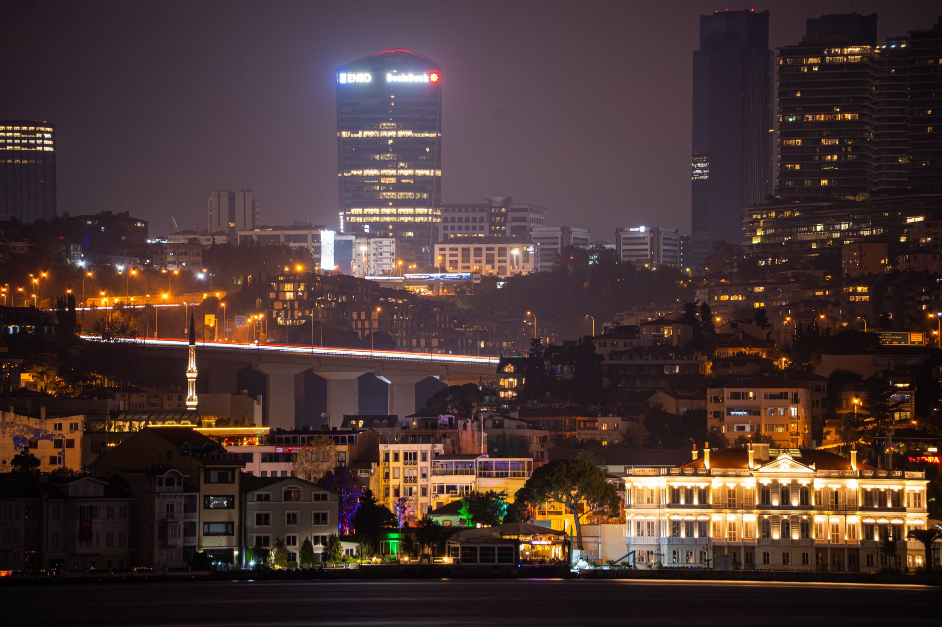 A view of Istanbul's skyline at night featuring a modern hospital and illuminated buildings.