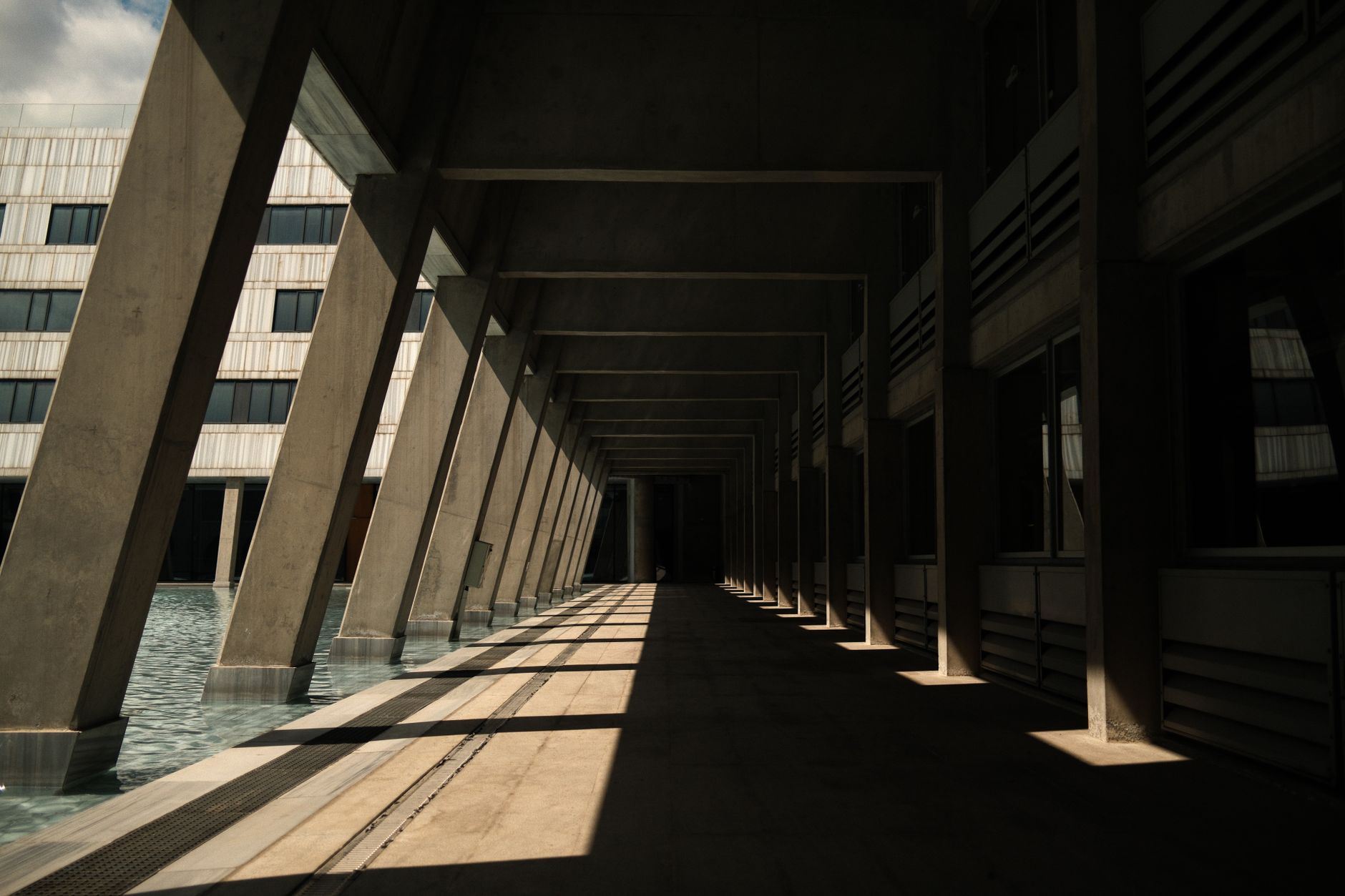Bright, modern hospital corridor in Ankara with concrete beams and reflective water.