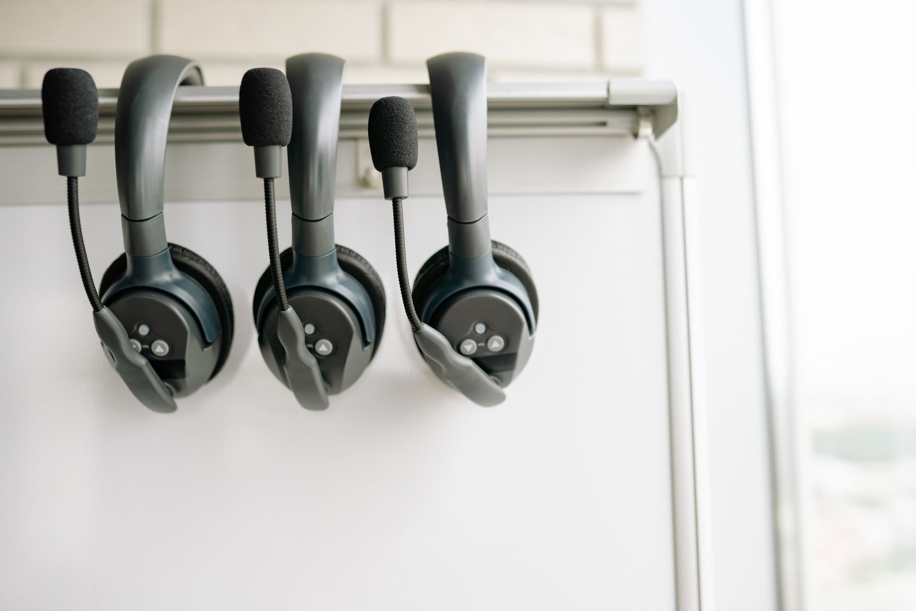 Close-up of three sleek wireless translation headsets displayed on a rack.