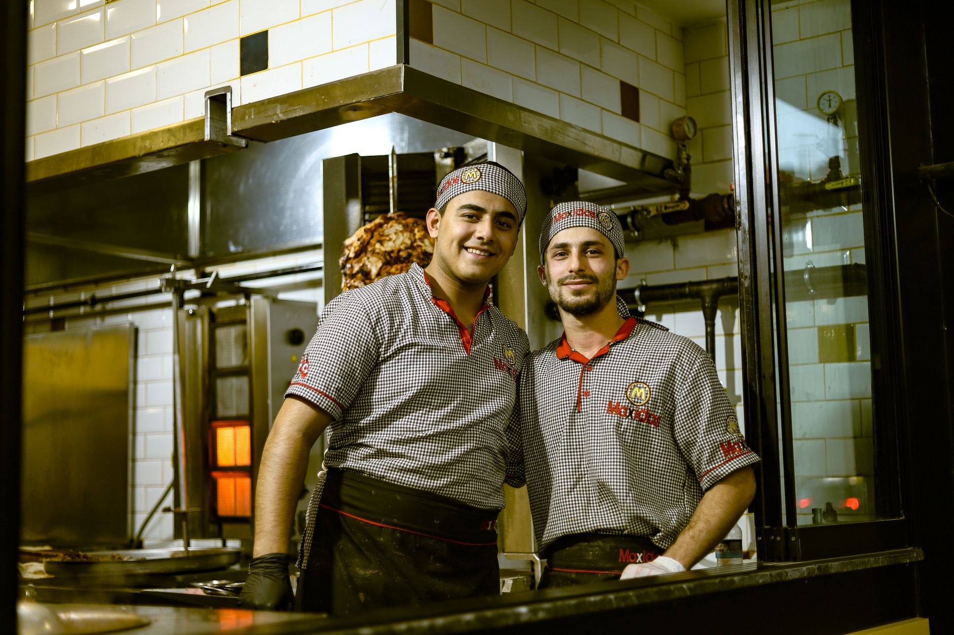 Two chefs smiling in a hospital kitchen, focused on preparing allergen-safe meals.