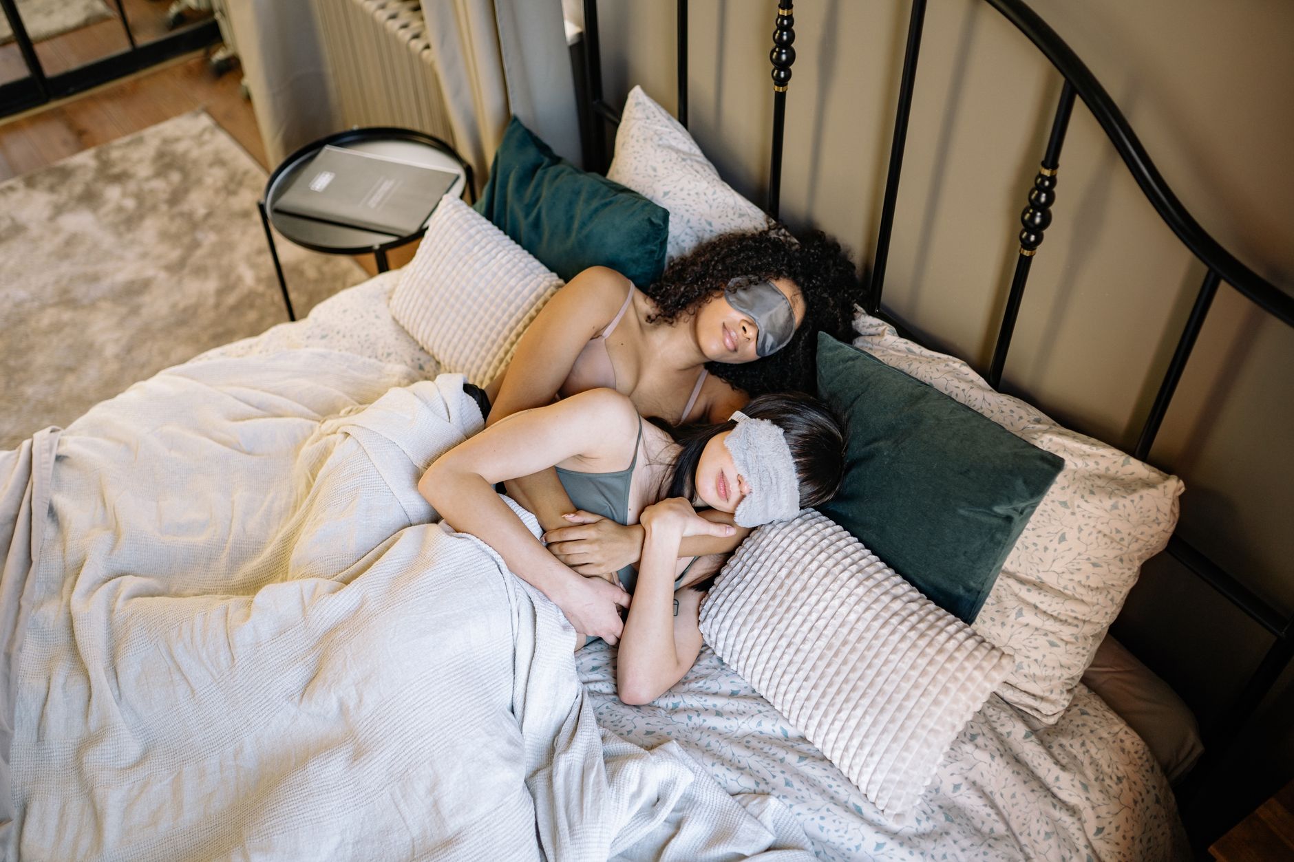 Two women peacefully sleeping together with sleep masks in a serene bedroom.