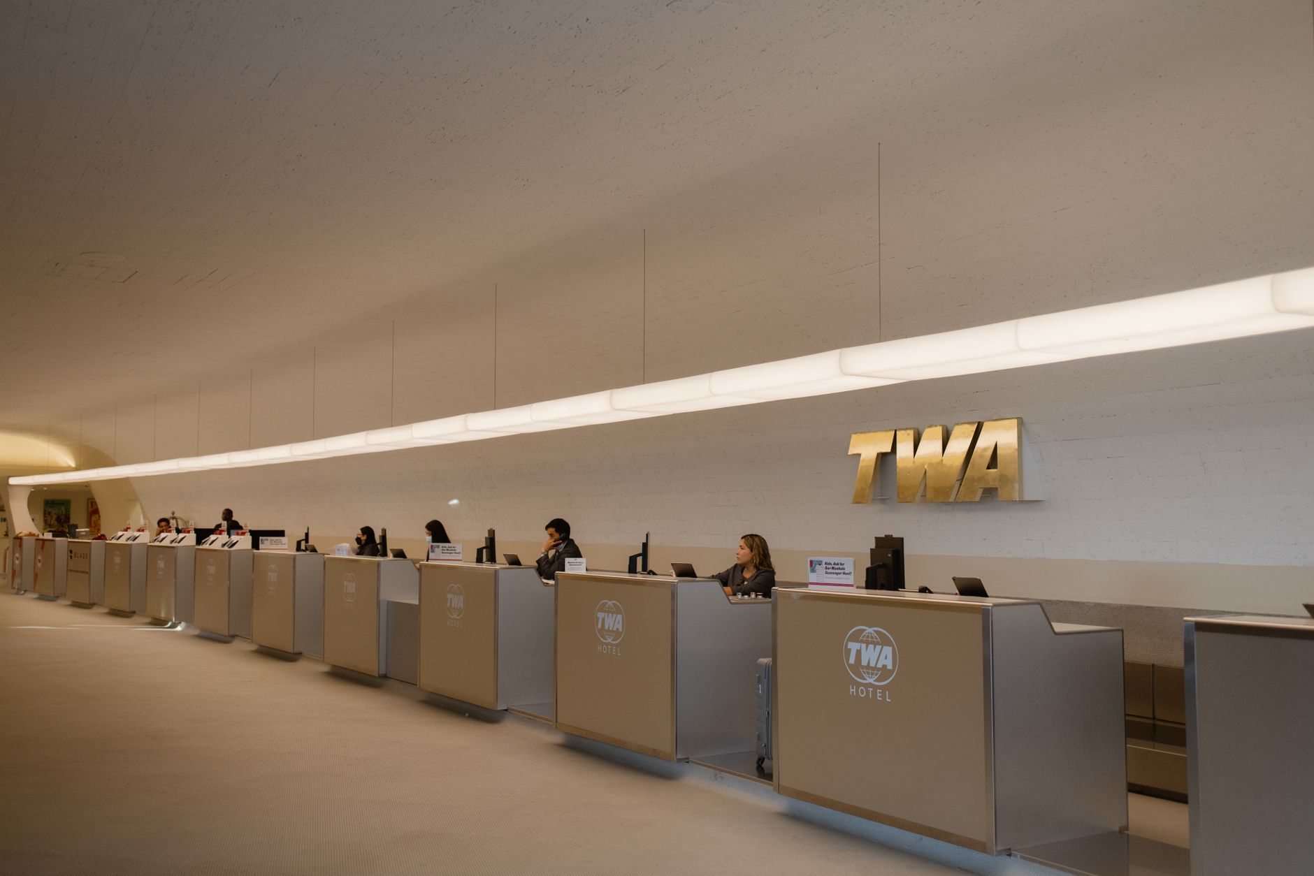 Reception area of the TWA Hotel at JFK Airport with staff ready to assist guests.