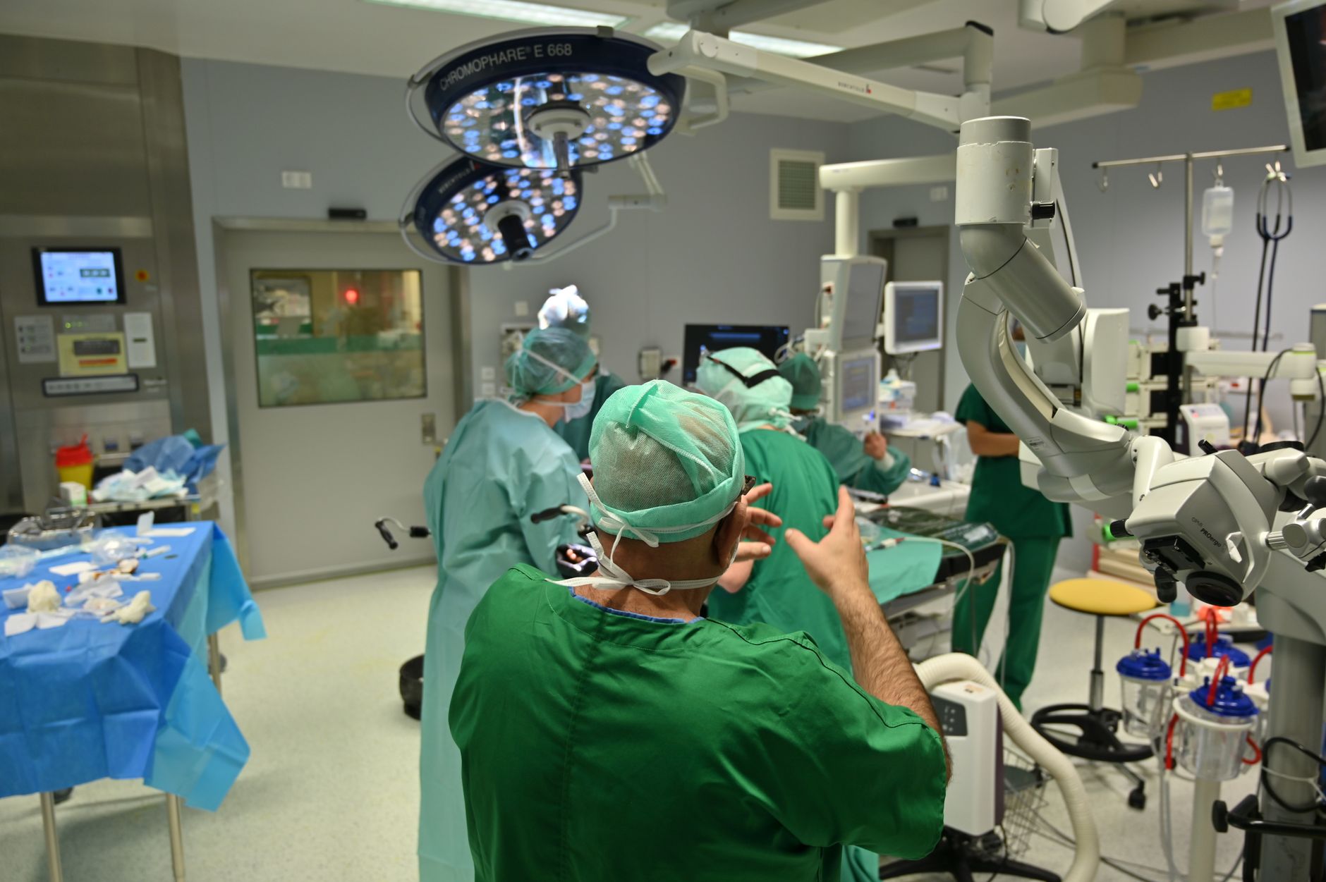 Surgeons in green scrubs collaborating in a high-tech operating room.