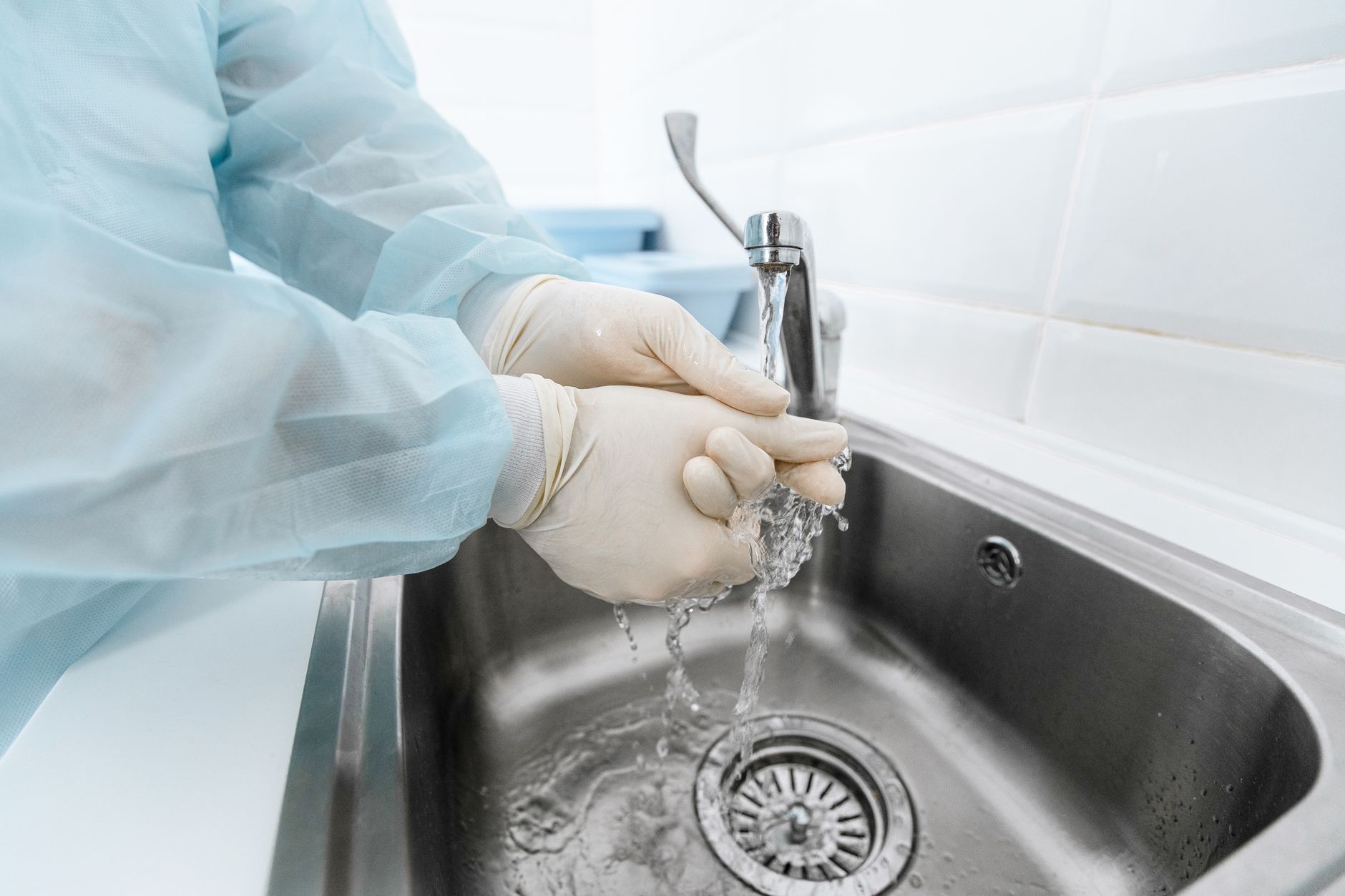 A healthcare worker in gloves washing hands at a hospital sanitizing station.