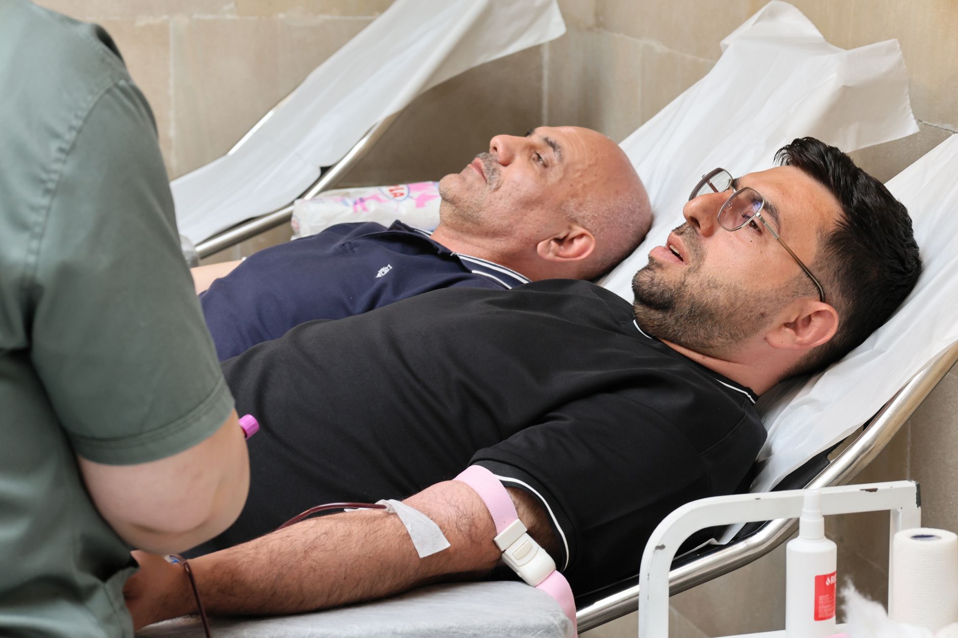 Two men receiving treatment while lying on beds at a healthcare facility.