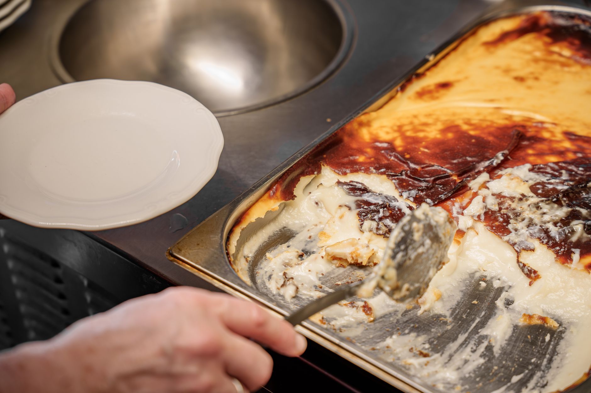 Hand serving a Turkish dish from a tray to a plate in a hospital setting.